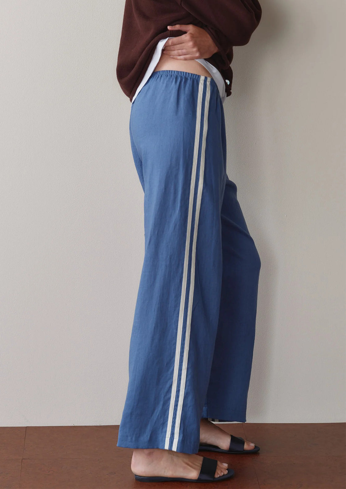Person wearing blue pants with white stripes against a plain background