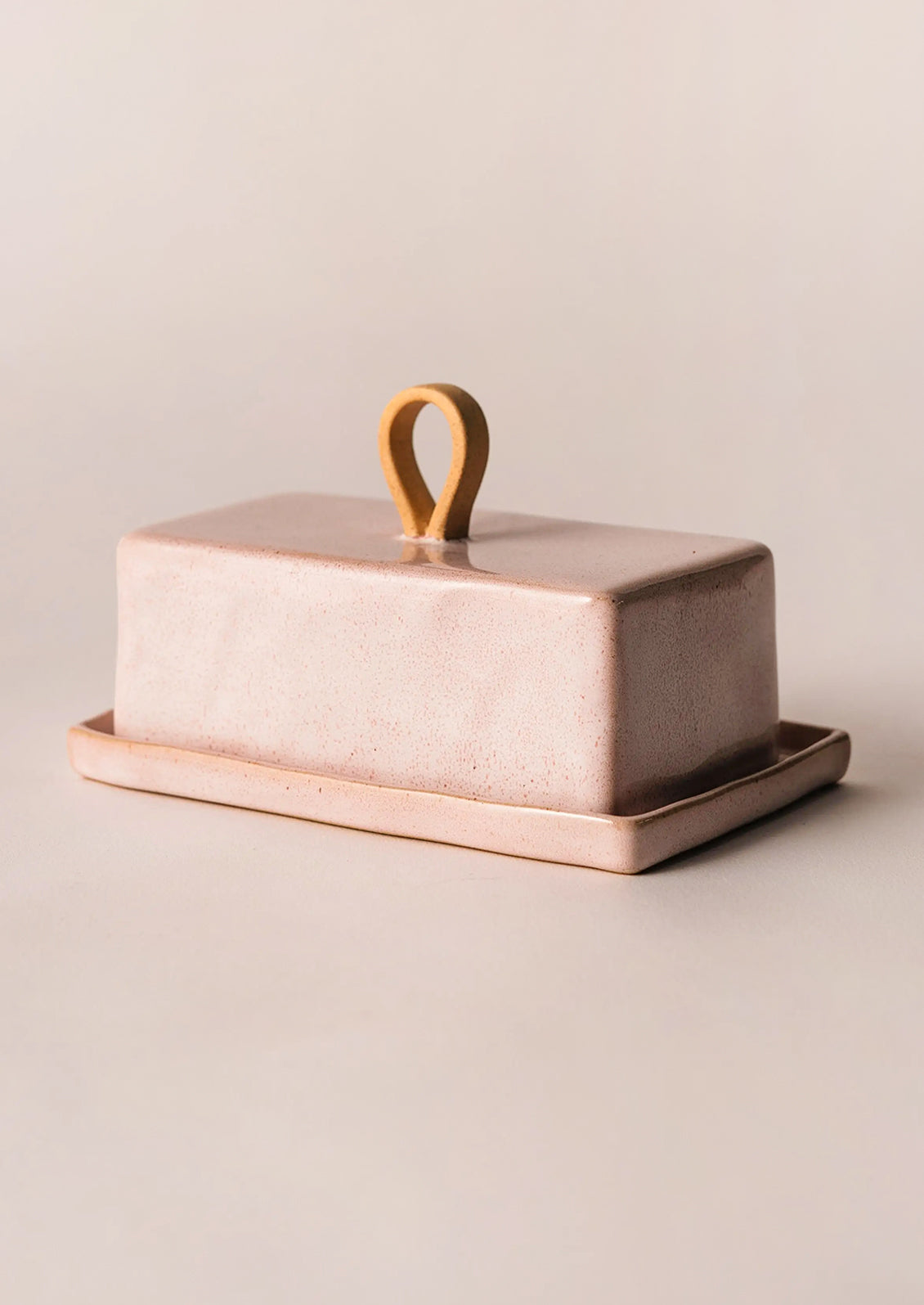 Ceramic butter dish with a lid and handle on a beige background
