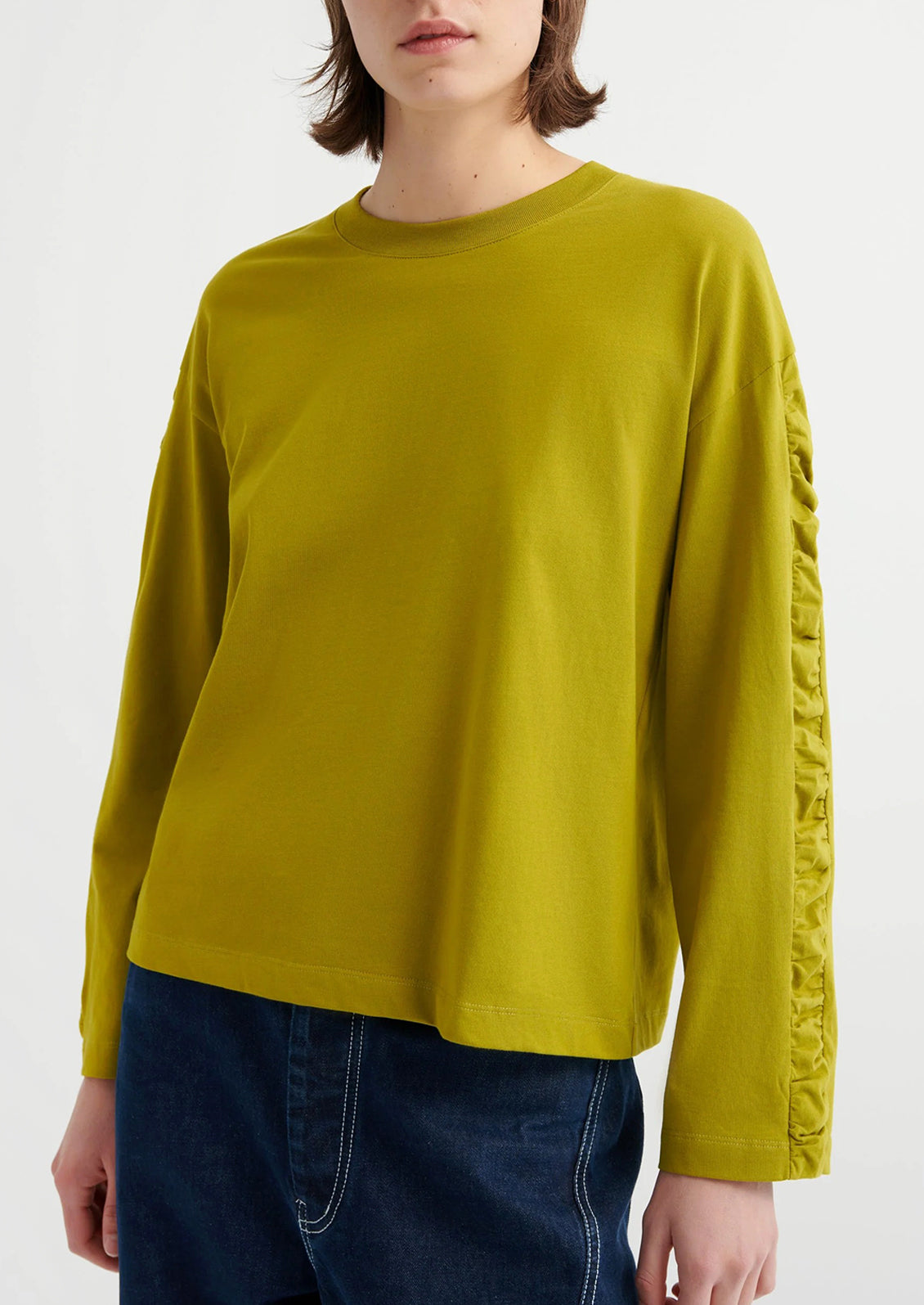 Person wearing a chartreuse long-sleeve shirt with a textured sleeve design on a white background