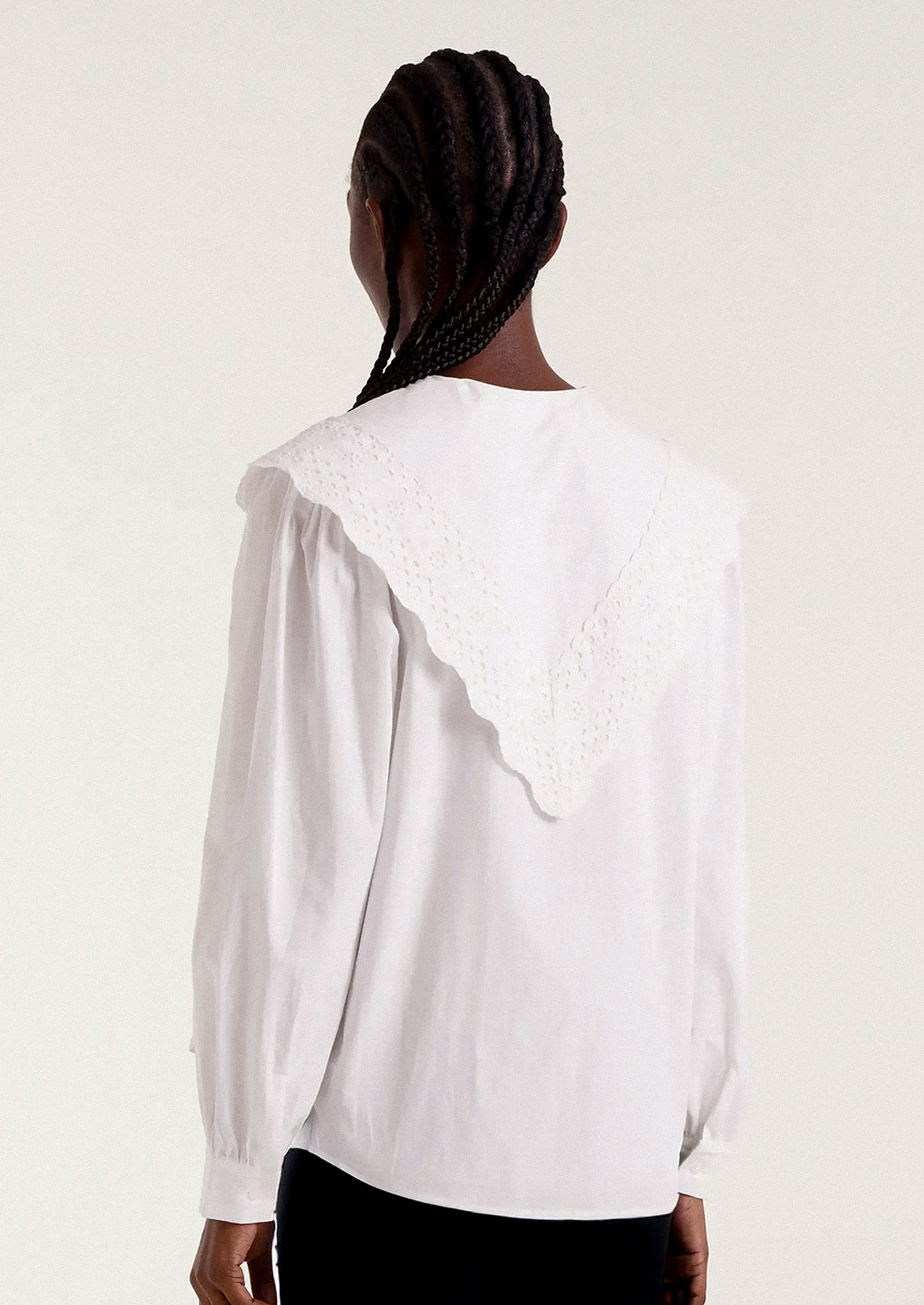 White blouse with intricate collar design worn by a person.