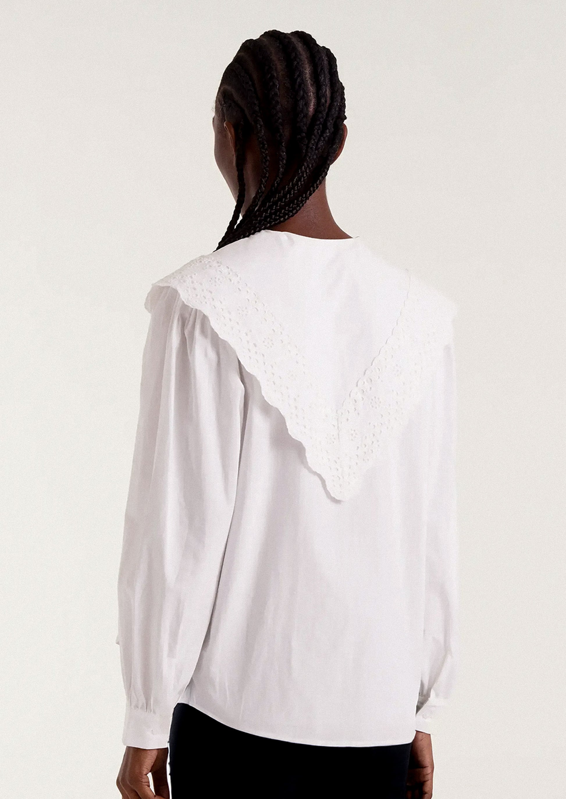 White blouse with intricate collar design worn by a person.