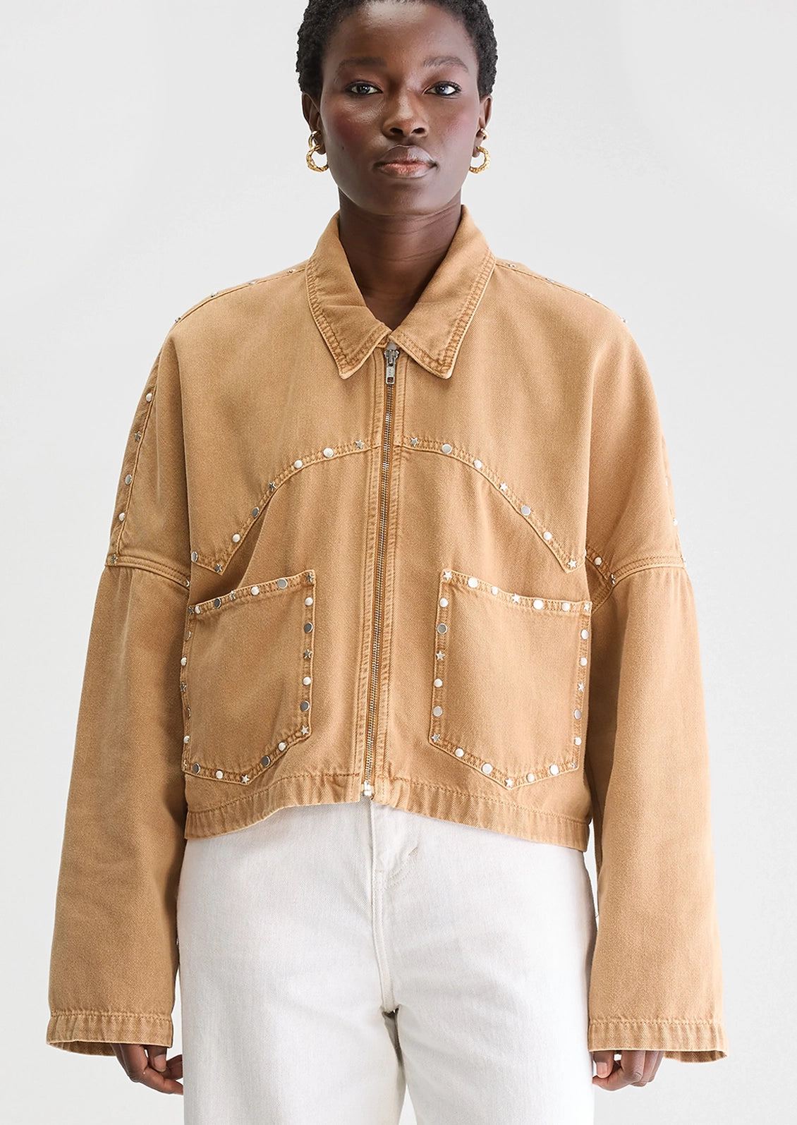 Person wearing a tan jacket with studded details.
