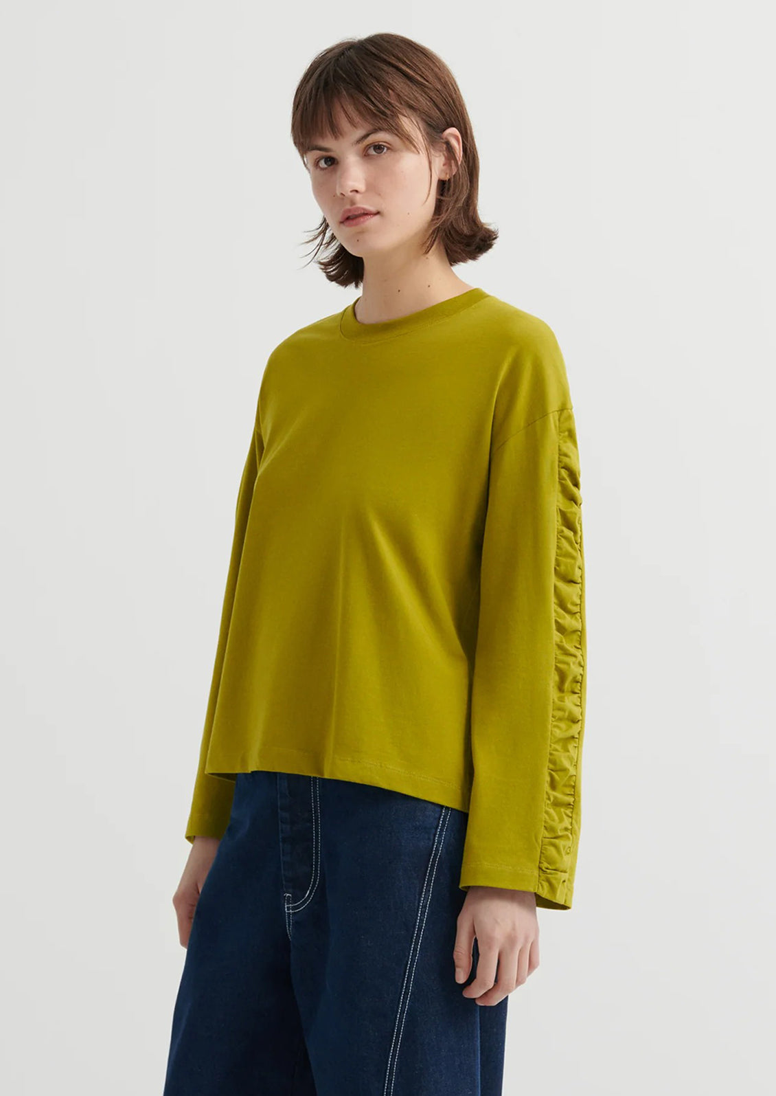 Person wearing a chartreuse long-sleeve shirt with a textured sleeve design on a white background