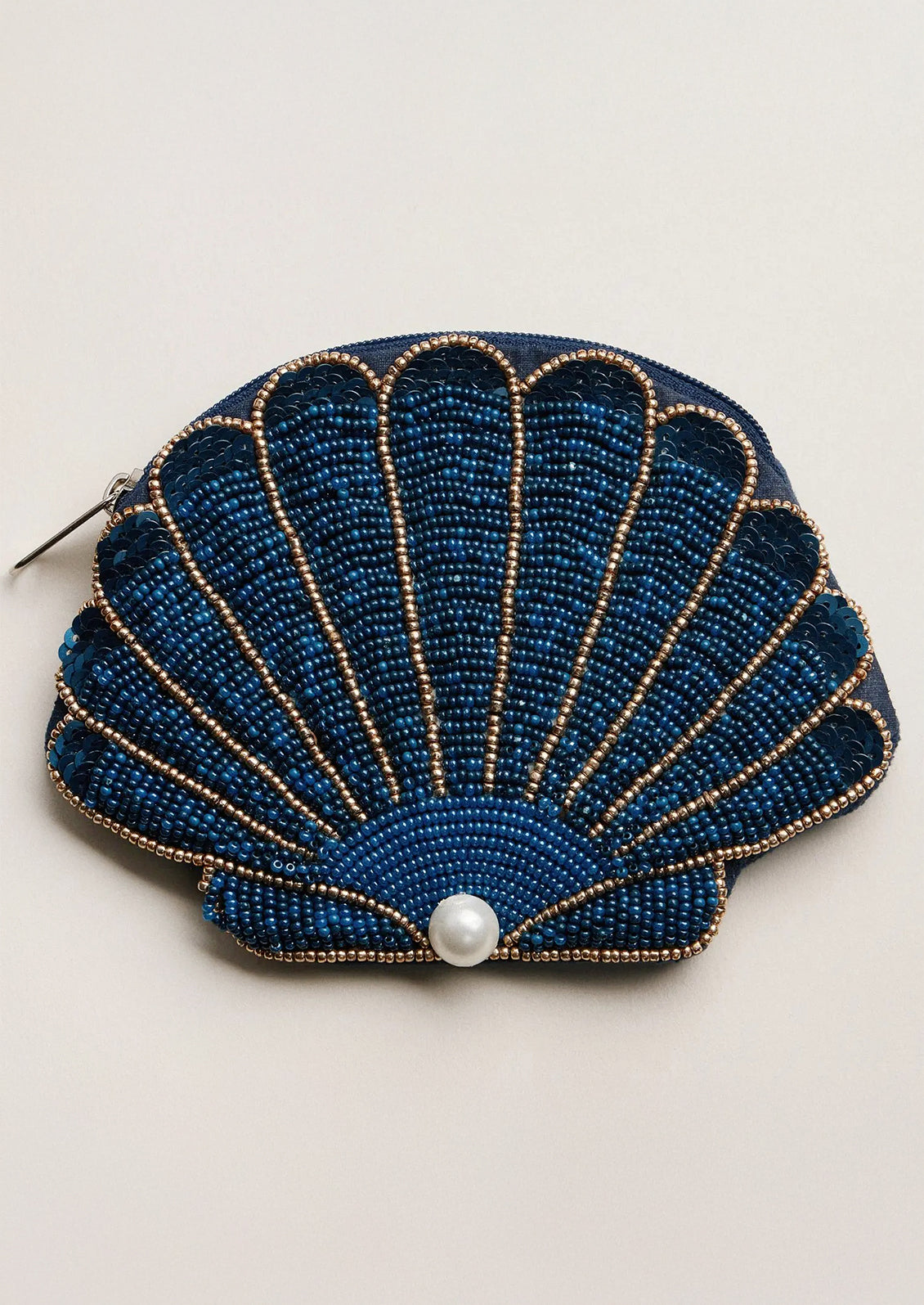 Blue beaded shell-shaped purse with a pearl on a beige background