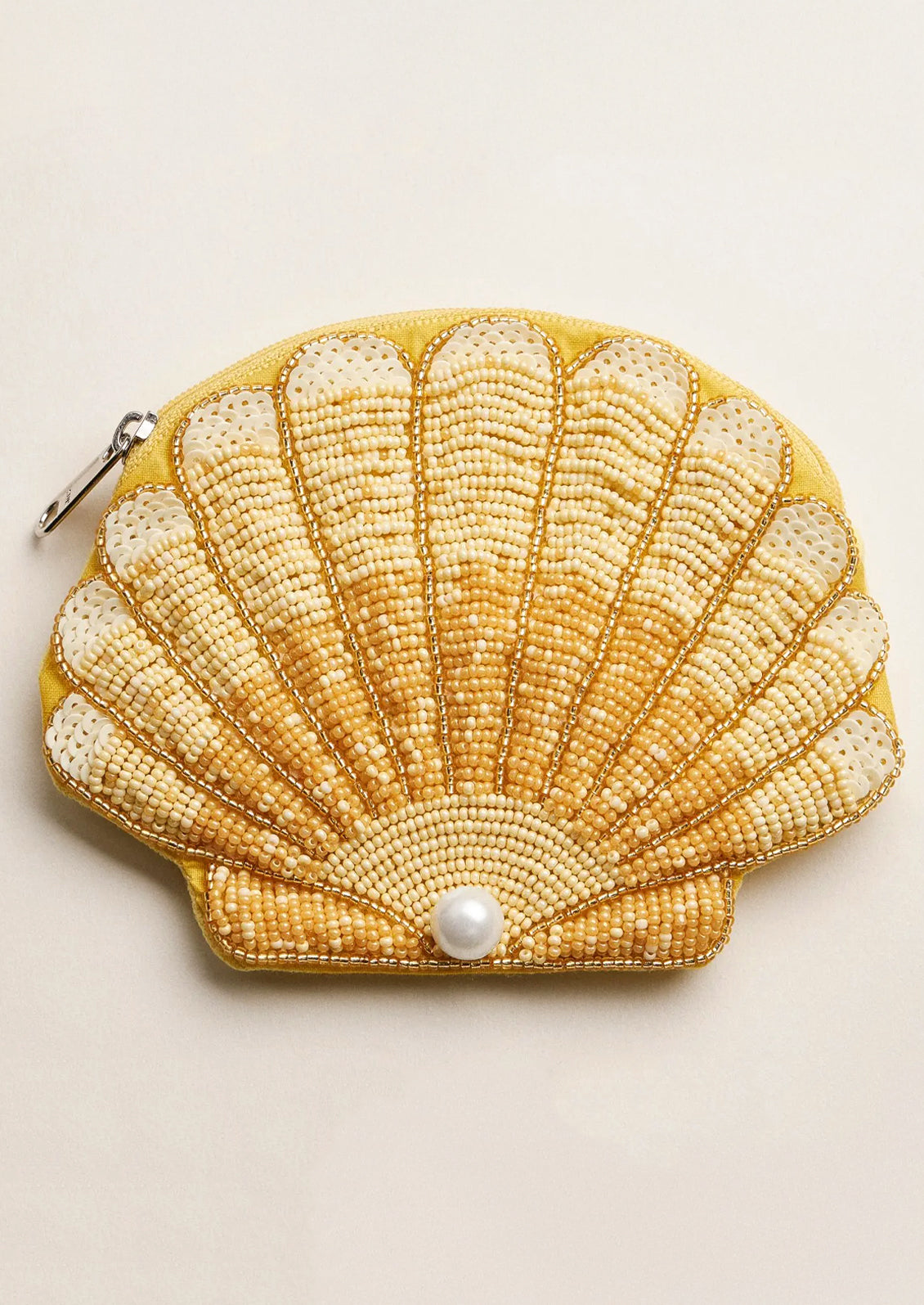 Shell-shaped beaded purse with a pearl on a beige background