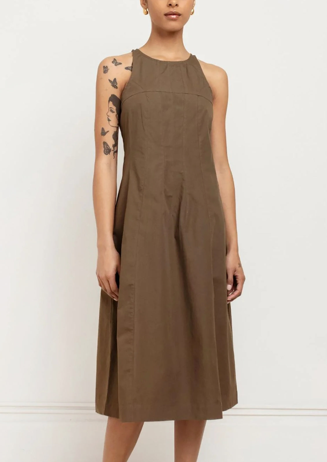 A person wearing a sleeveless dress in olive color.