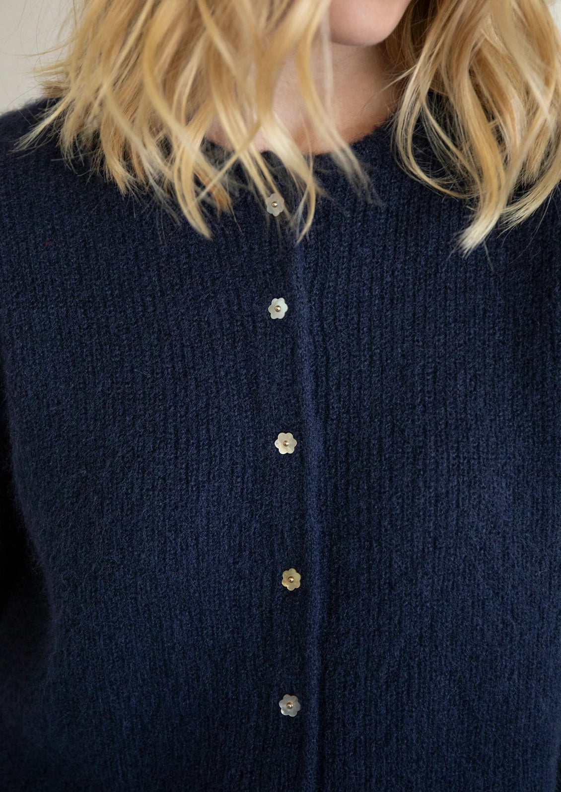 A navy blue knit cardigan sweater with mother of pearl flower shaped buttons.