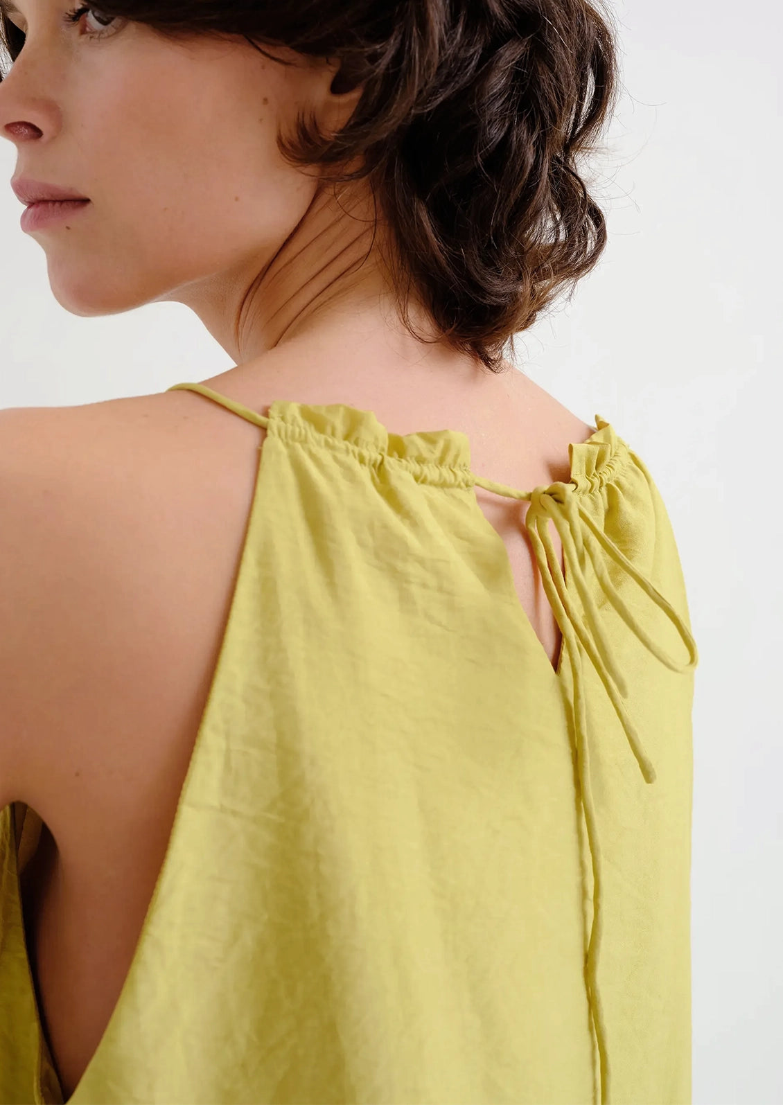 Woman wearing a chartreuse sleeveless top on a white background