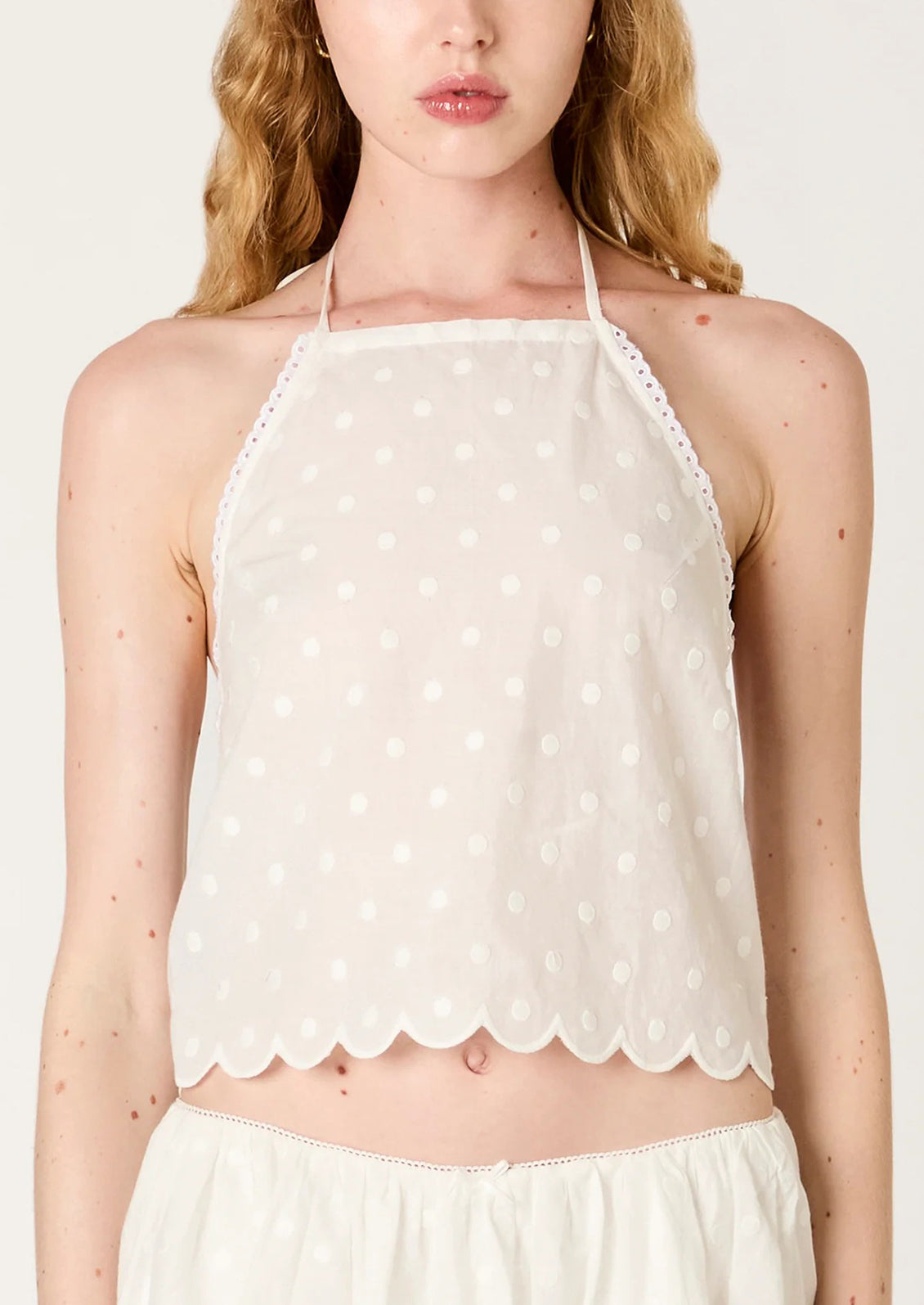 White polka dot halter top worn by a model on a plain background