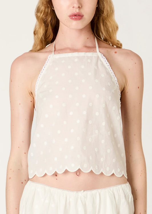 White polka dot halter top worn by a model on a plain background