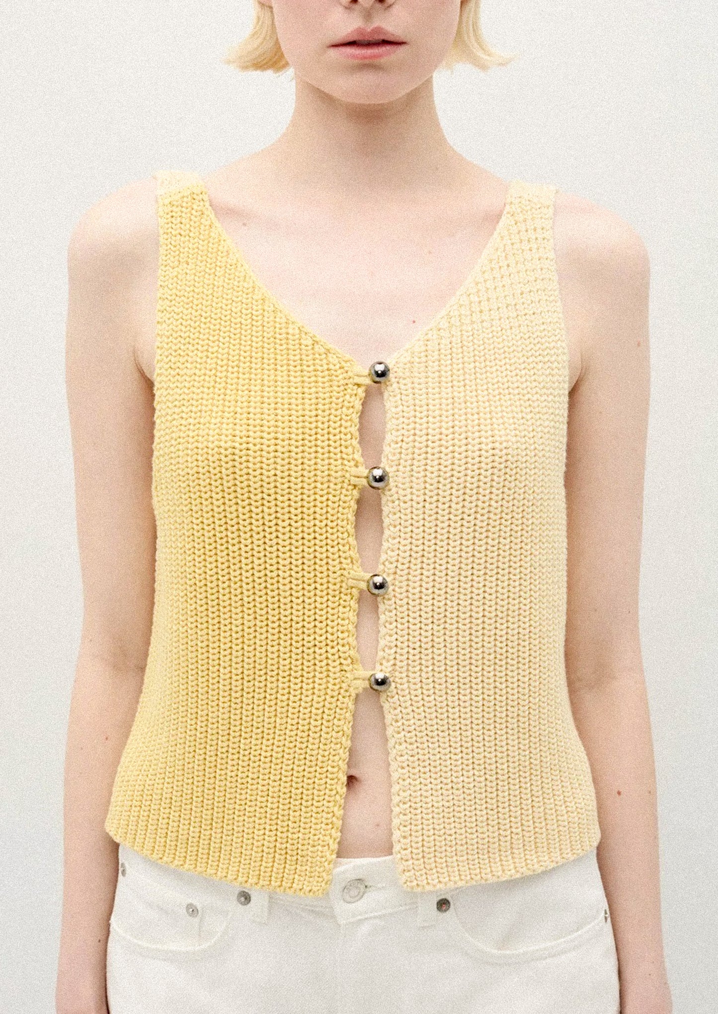 A person wearing a sleeveless knit vest in two tone yellow.