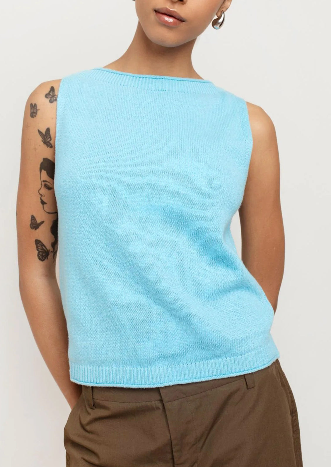 A person wearing a knit top with high neckline in bright cyan color.