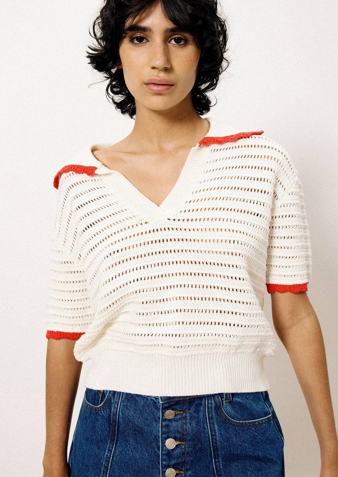 A short sleeve sweater in white open weave with red trim.