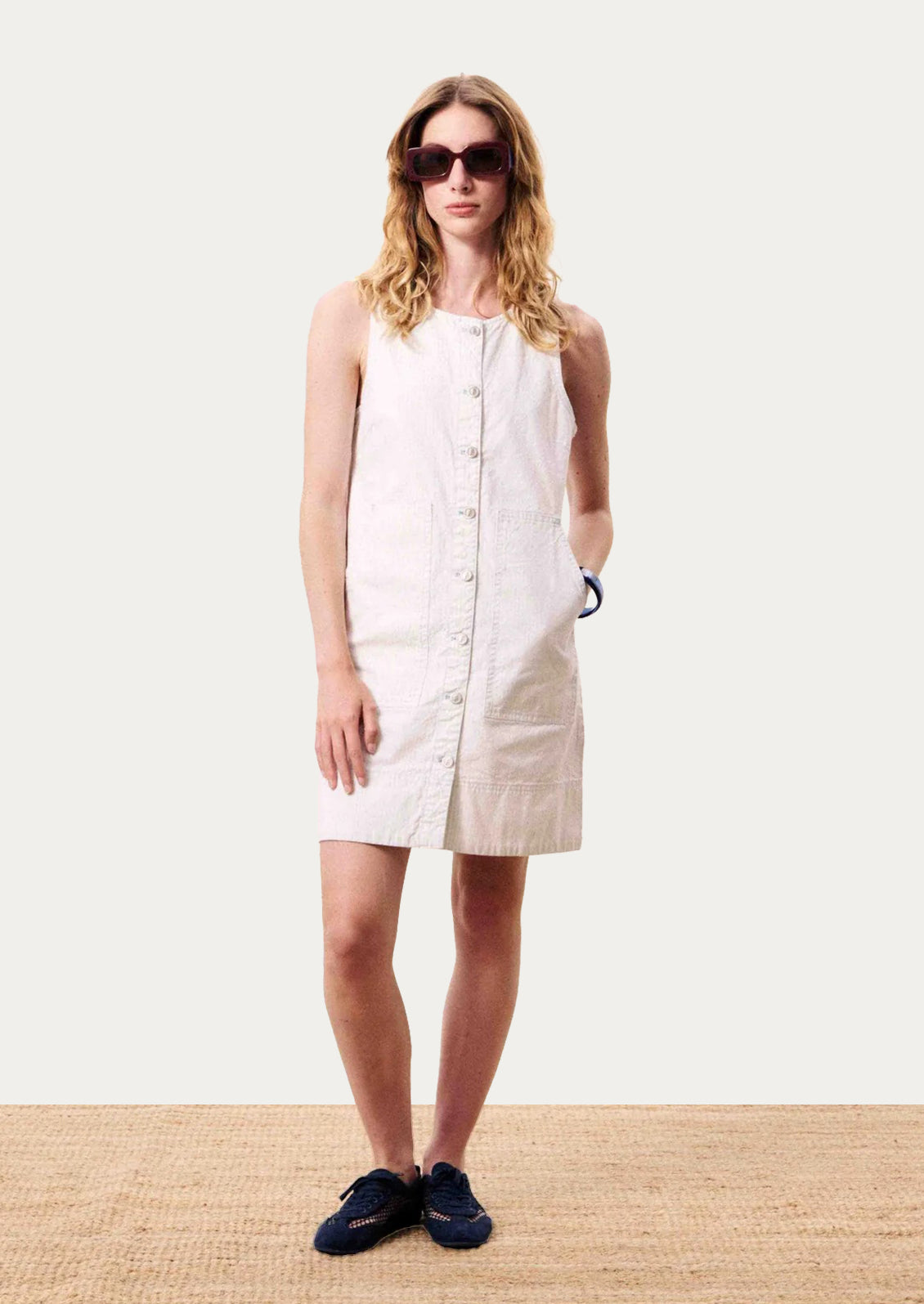 Woman wearing a white sleeveless dress on a plain background