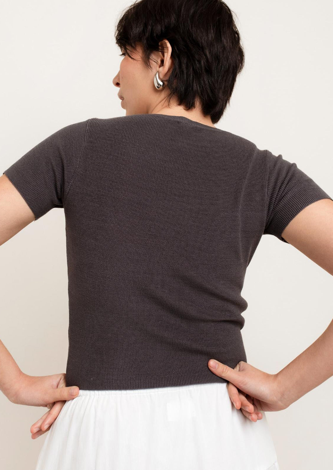 A person wearing a knit cropped t-shirt in grey.