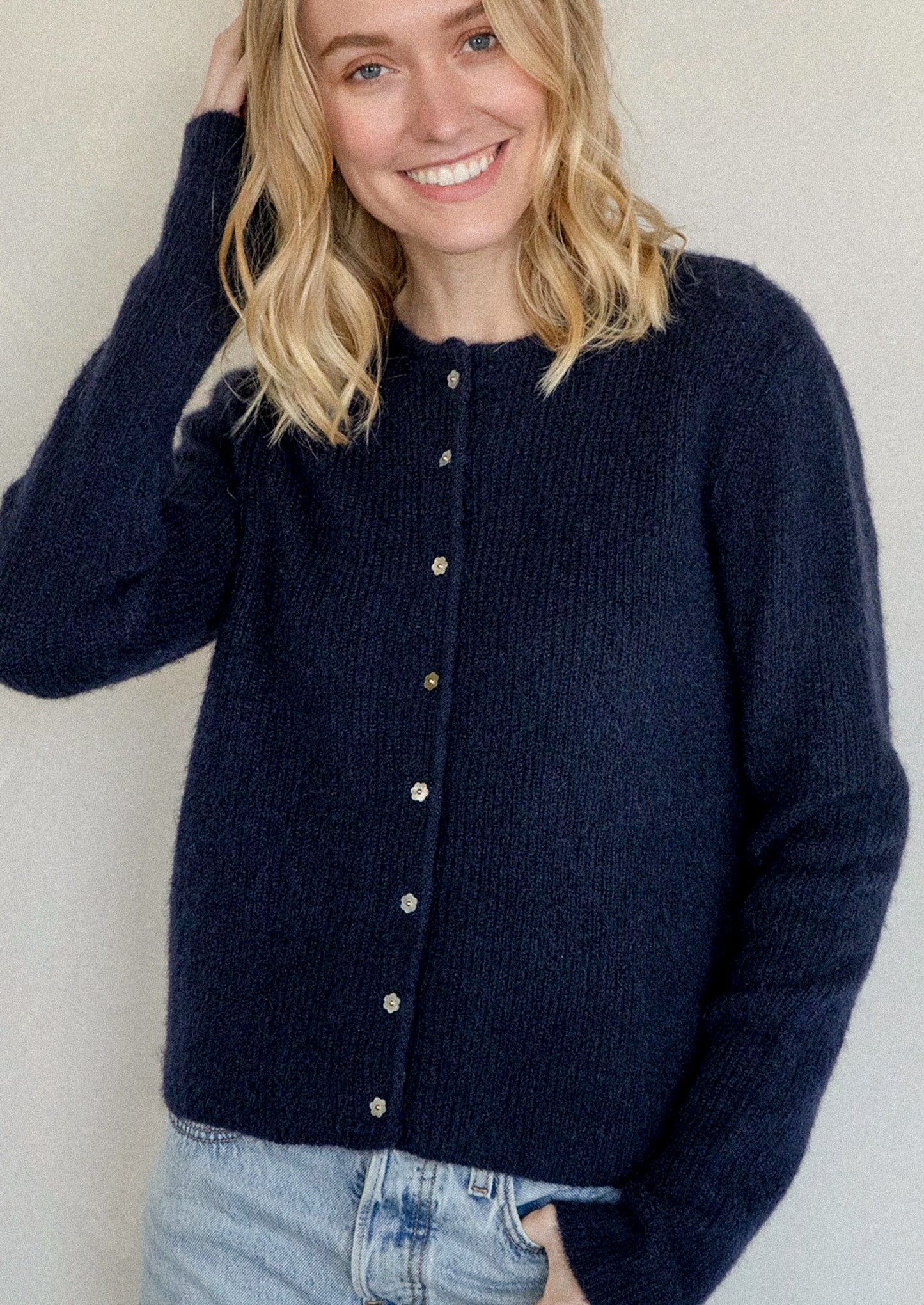 A navy blue knit cardigan sweater with mother of pearl flower shaped buttons.