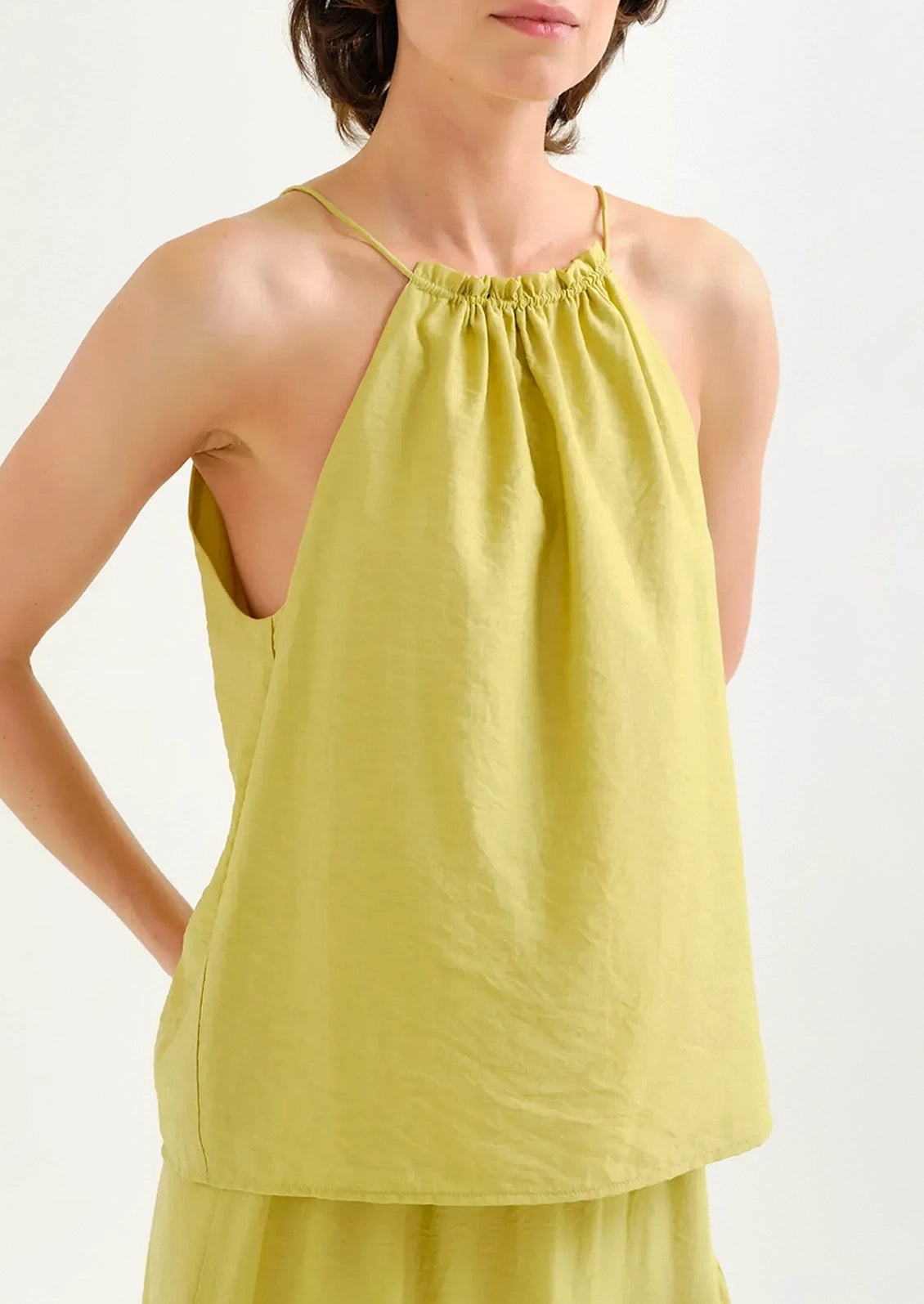 Woman wearing a chartreuse sleeveless top on a white background