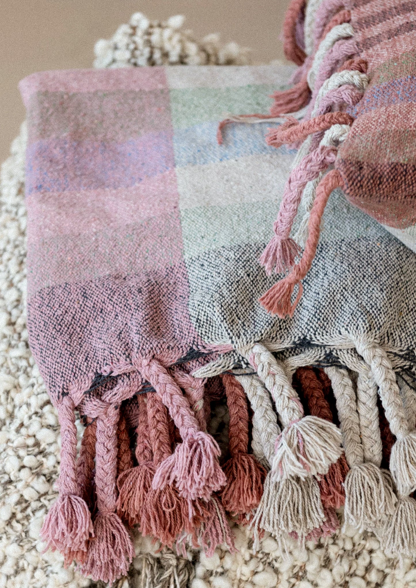 A cotton throw blanket with madras check pattern in shades of pink.