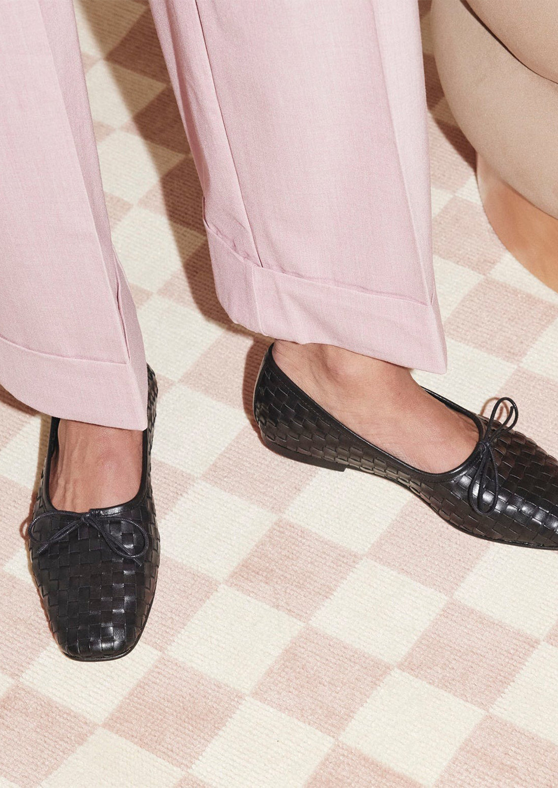 A pair of square toe ballet flats with bow tie in black woven leather.