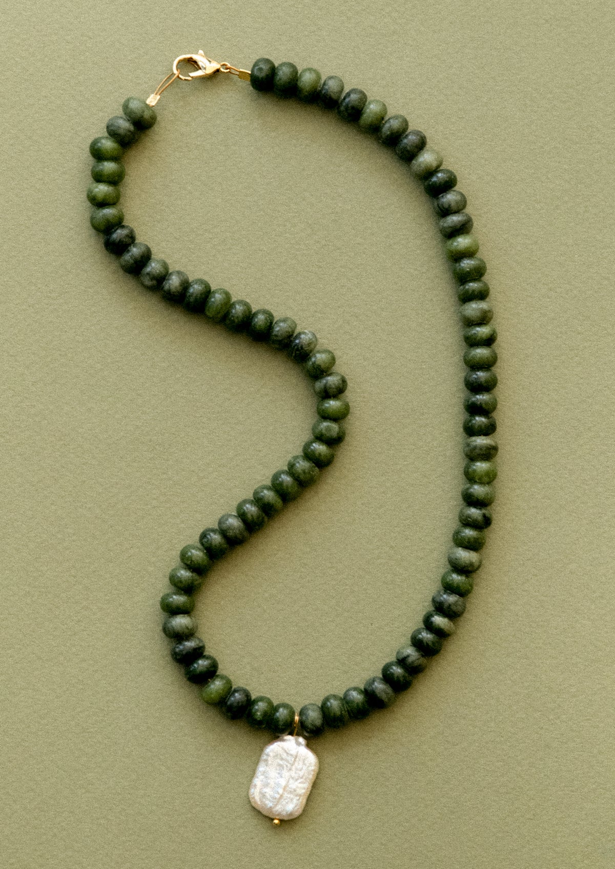 A  necklace with jade beads and pearl pendant.