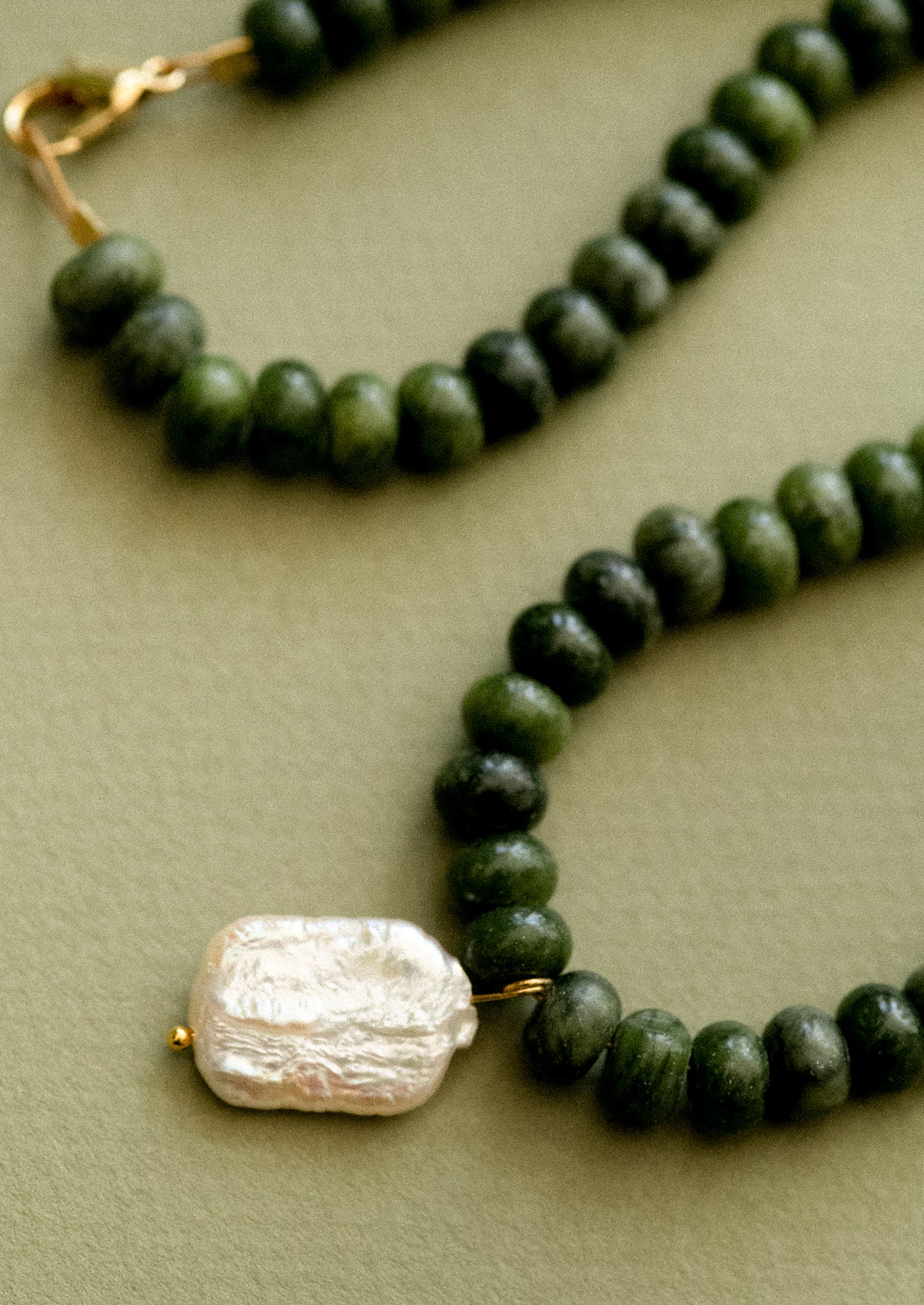 A  necklace with jade beads and pearl pendant.