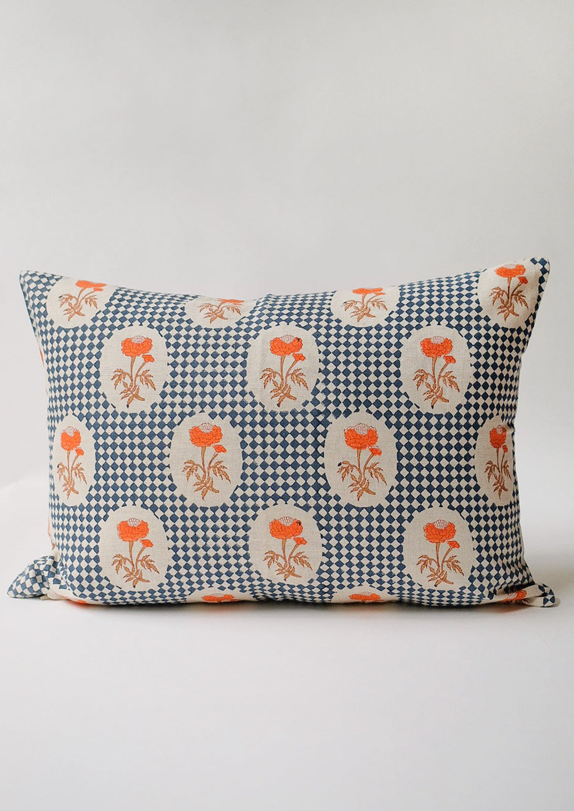 A block printed lumbar pillow with navy diamond checker and orange floral pattern.