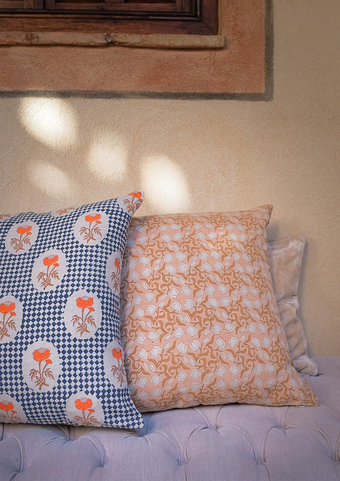 A block printed lumbar pillow with navy diamond checker and orange floral pattern.
