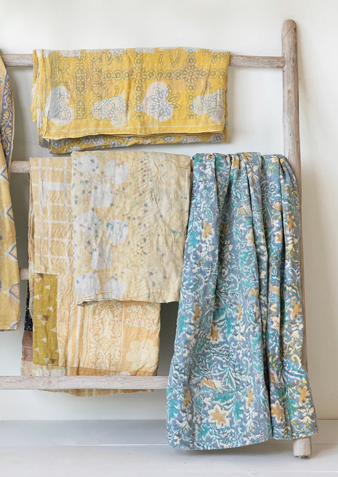 Different vintage kantha throws in yellow, periwinkle and blue colors.