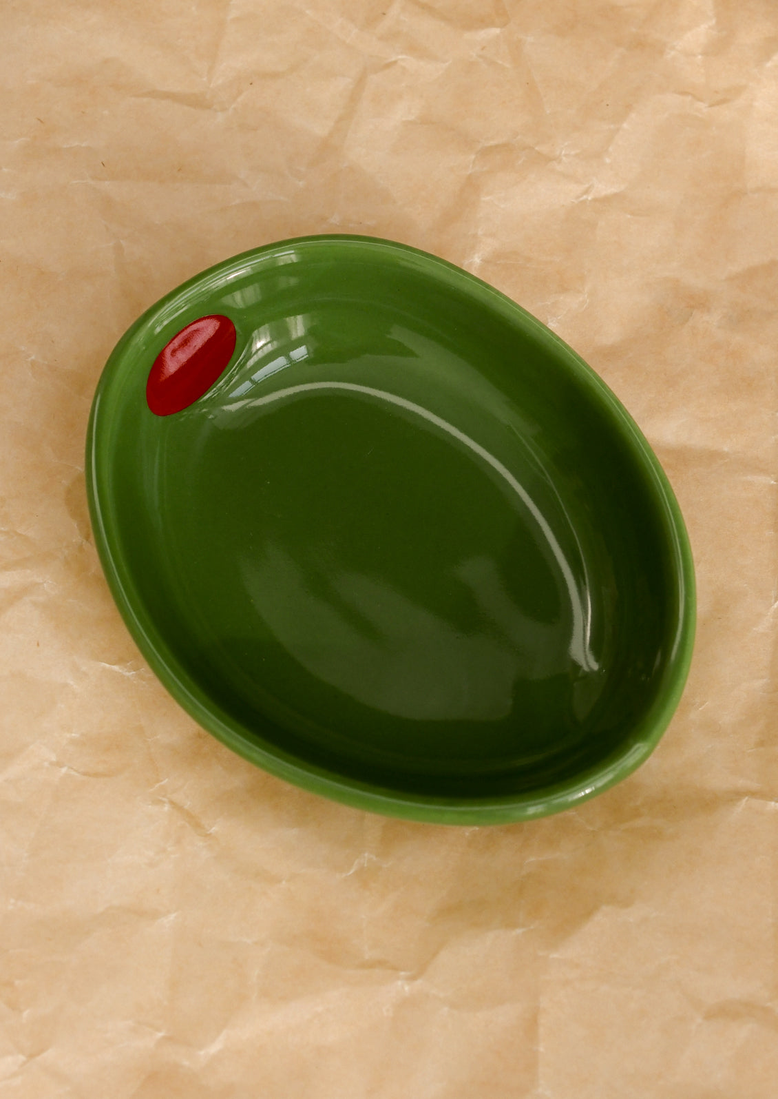 A small ceramic bowl shaped like an olive in kelly green.