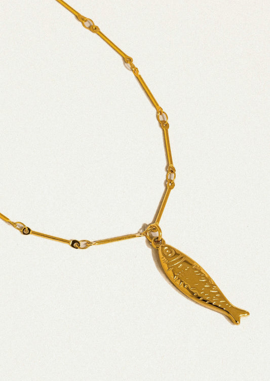 A gold necklace with a fish pendant.