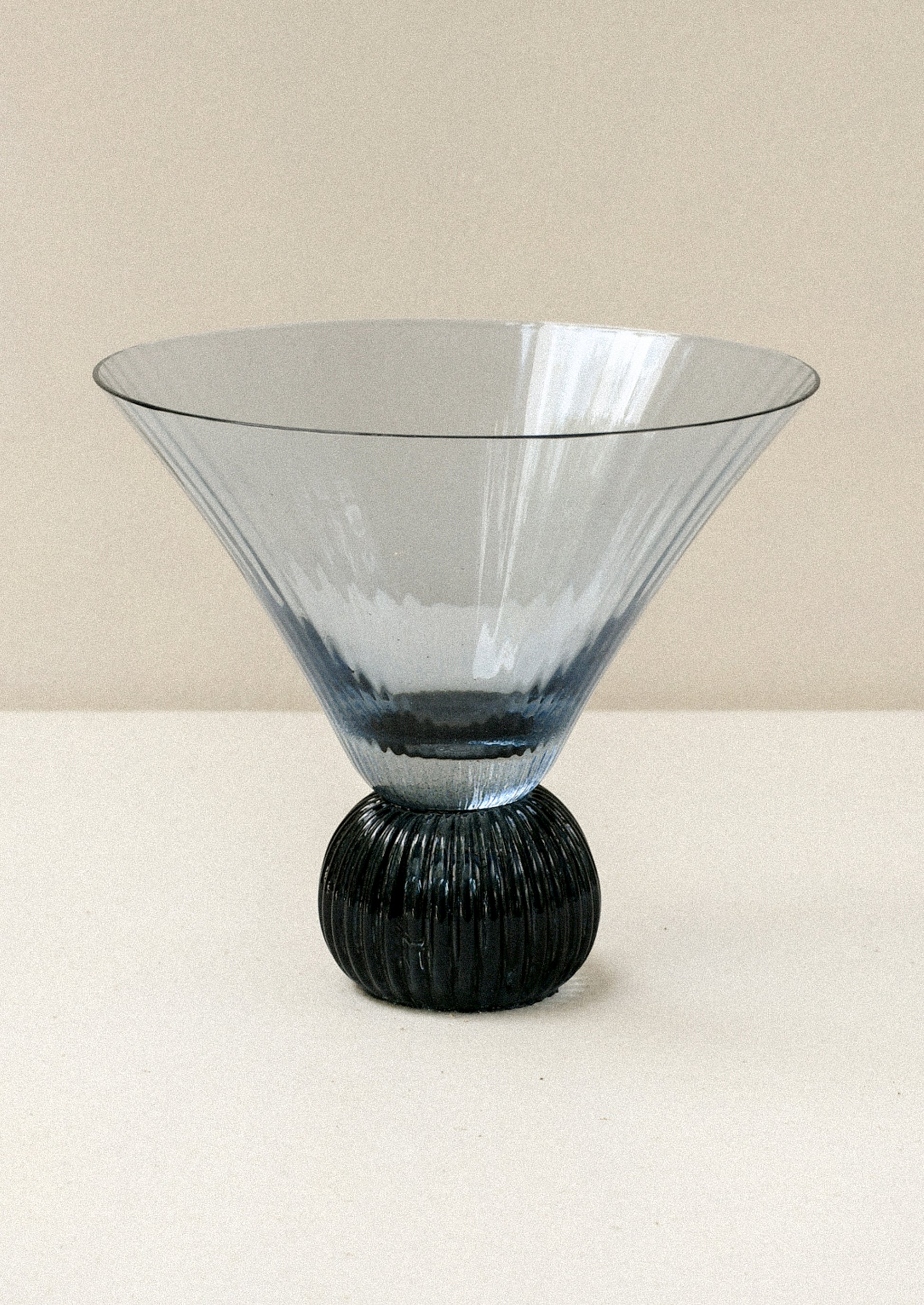 A short blue glass martini glass with ribbed, flared shape.