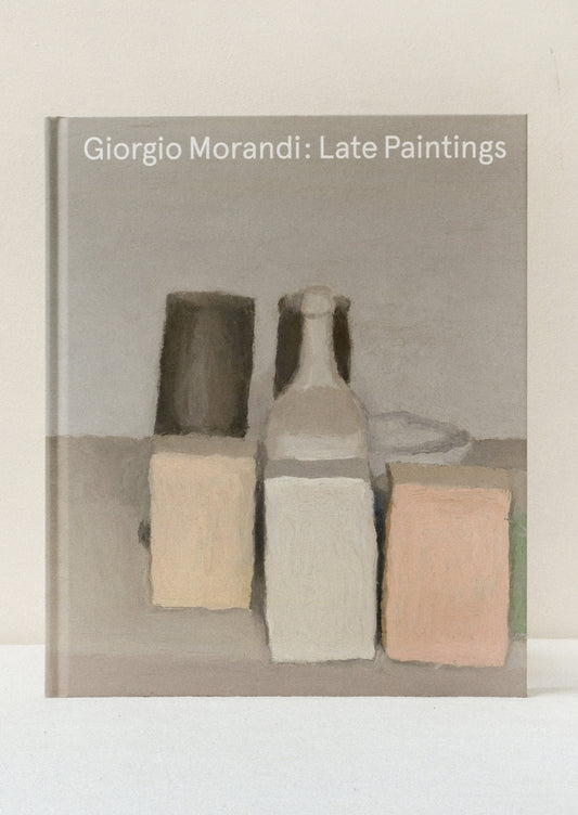 A hardcover book standing on a table titled "Giorgio Morandi: Late Paintings" with one of his paintings on the front.