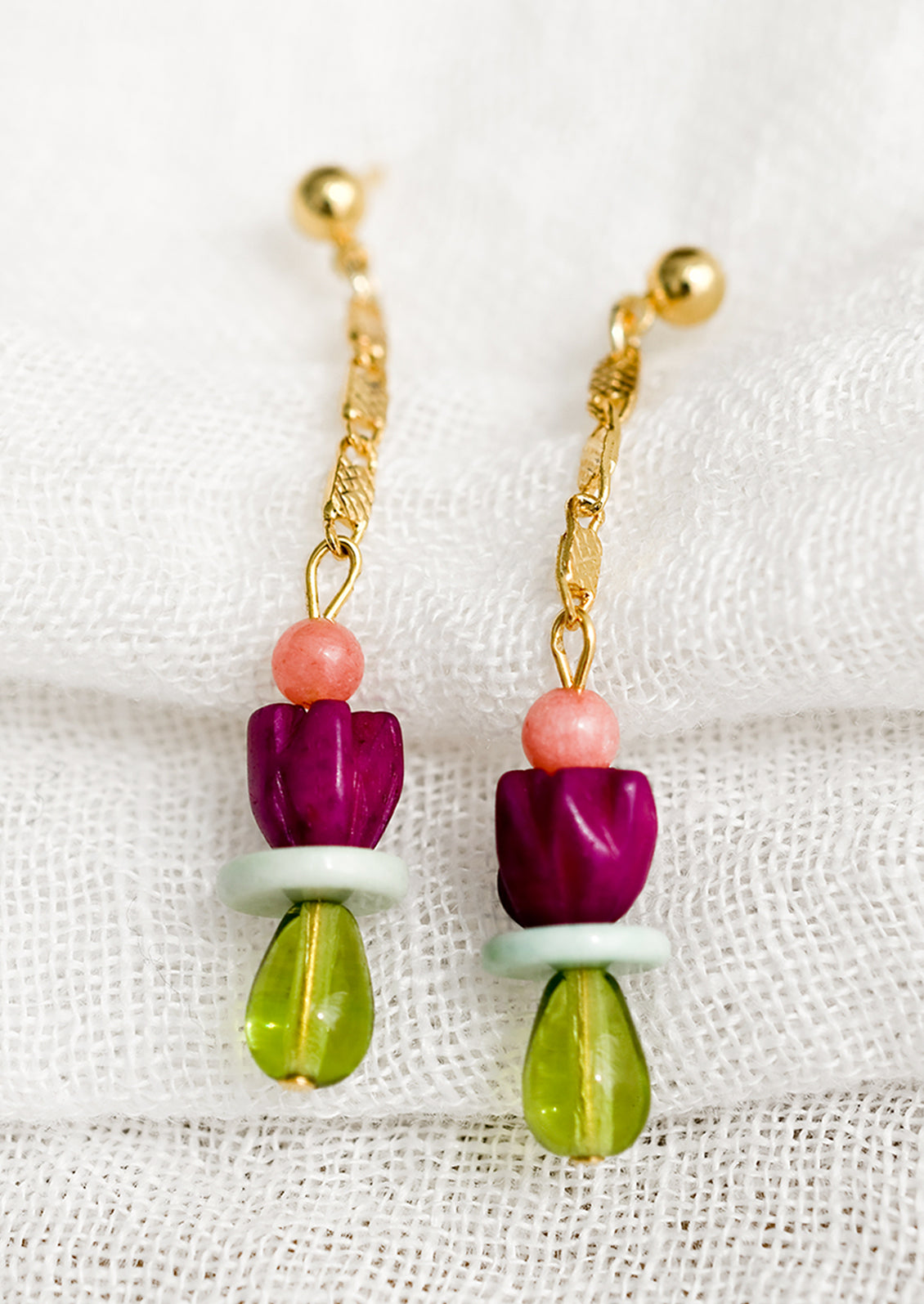 A pair of drop earrings with gold chain and beads.