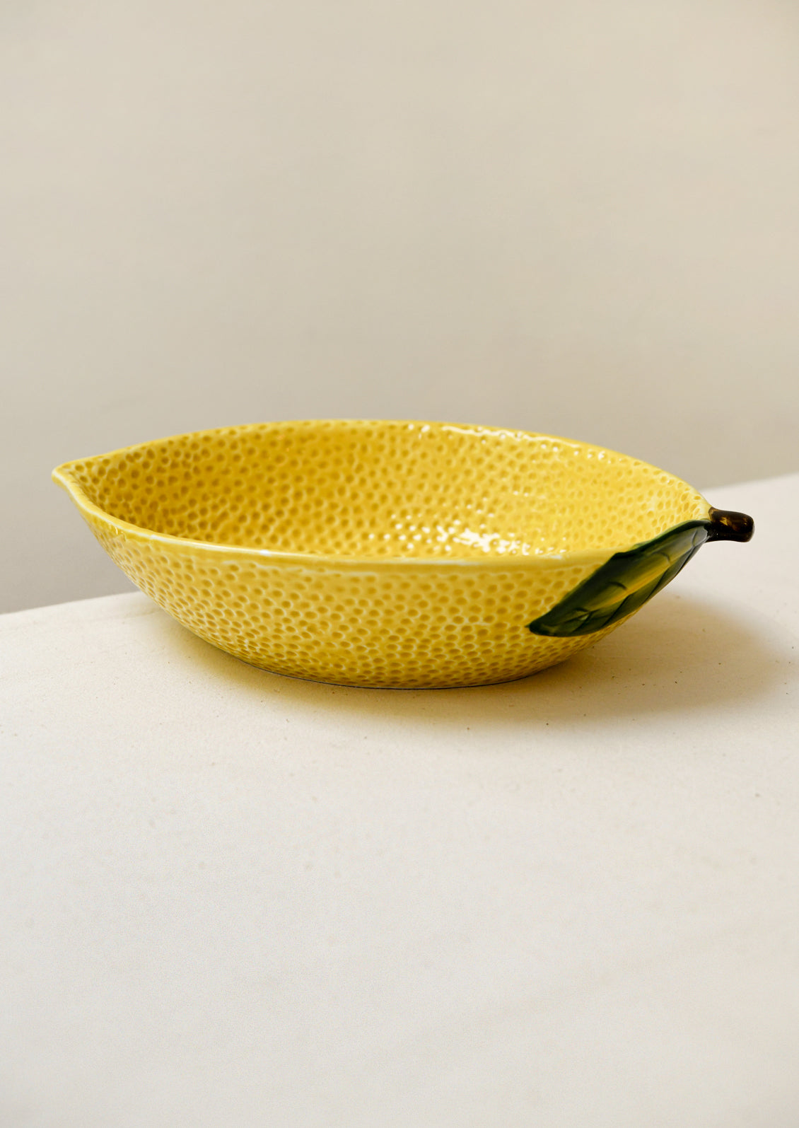 A large ceramic serving bowl in the shape of a lemon.
