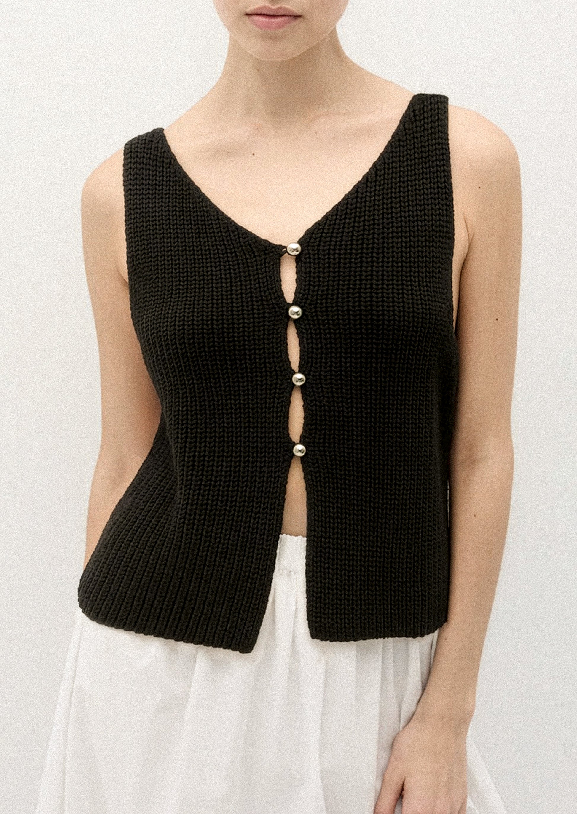 A person wearing a sleeveless knit vest in black.