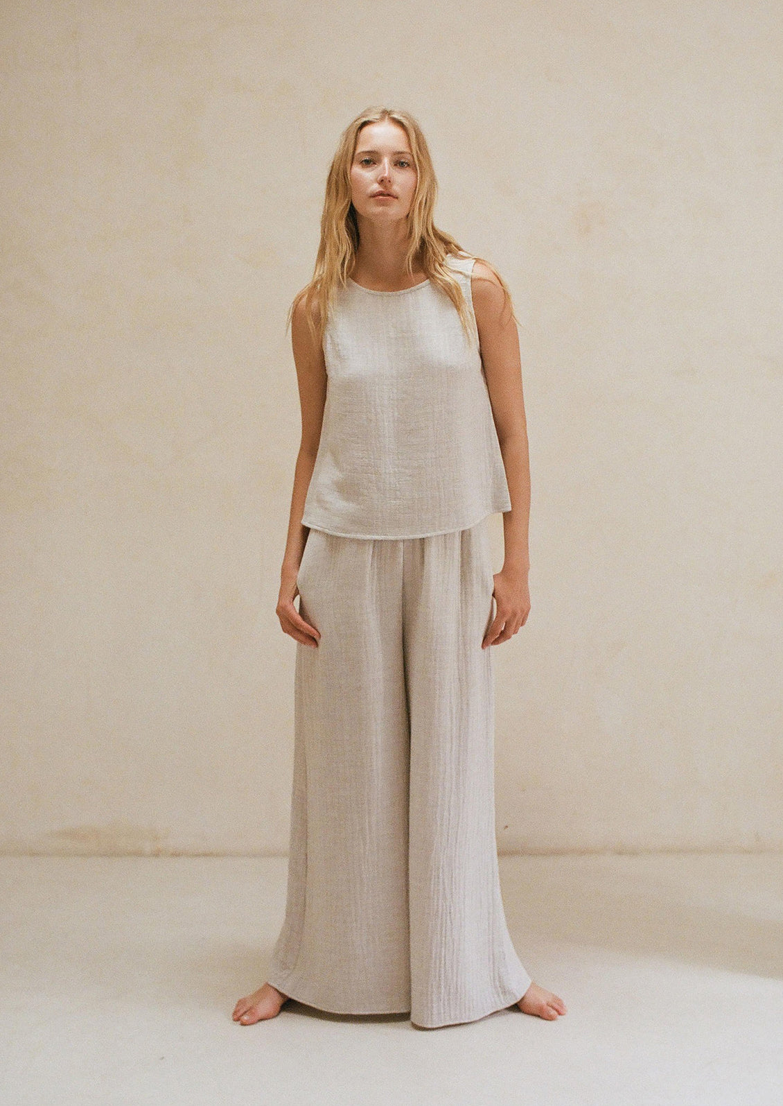 Woman wearing grey linen tank top and matching pants. 
