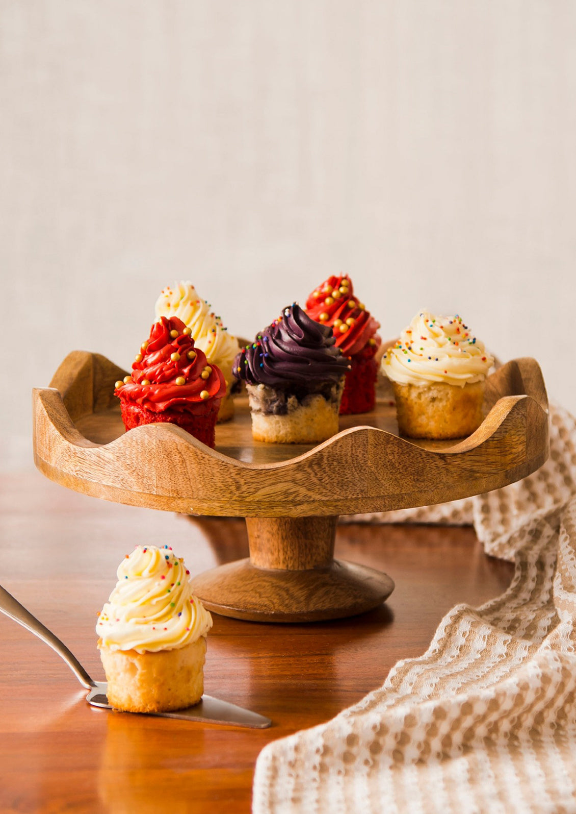 A mango wood cake stand with scalloped wavy edges.