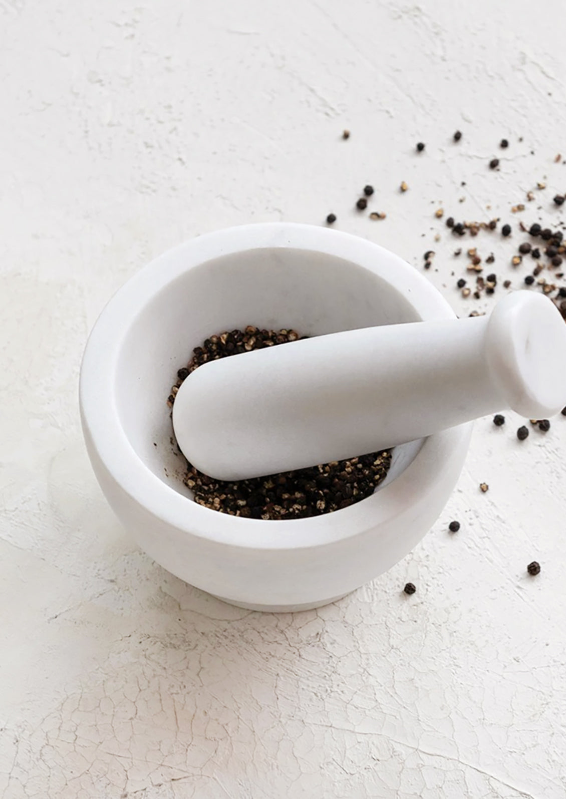 A mortar and pestle in solid white marble.