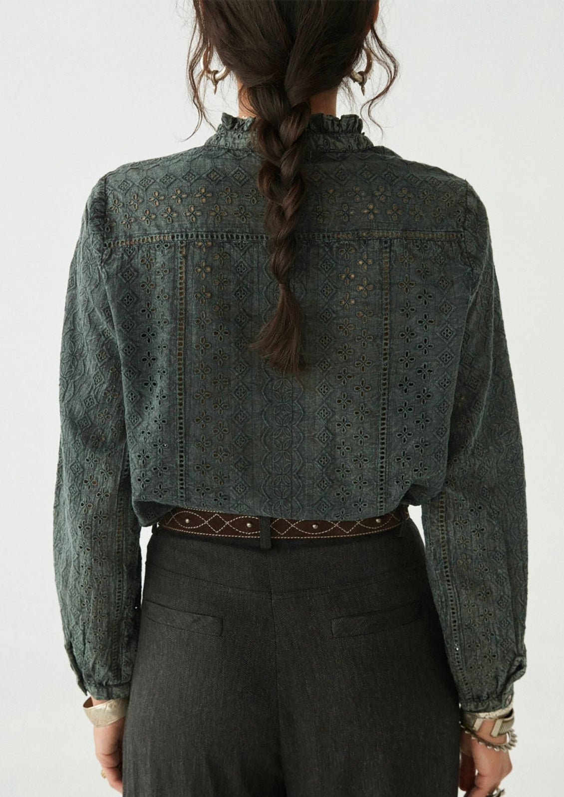 A woman wearing a dark grey cotton eyelet blouse.