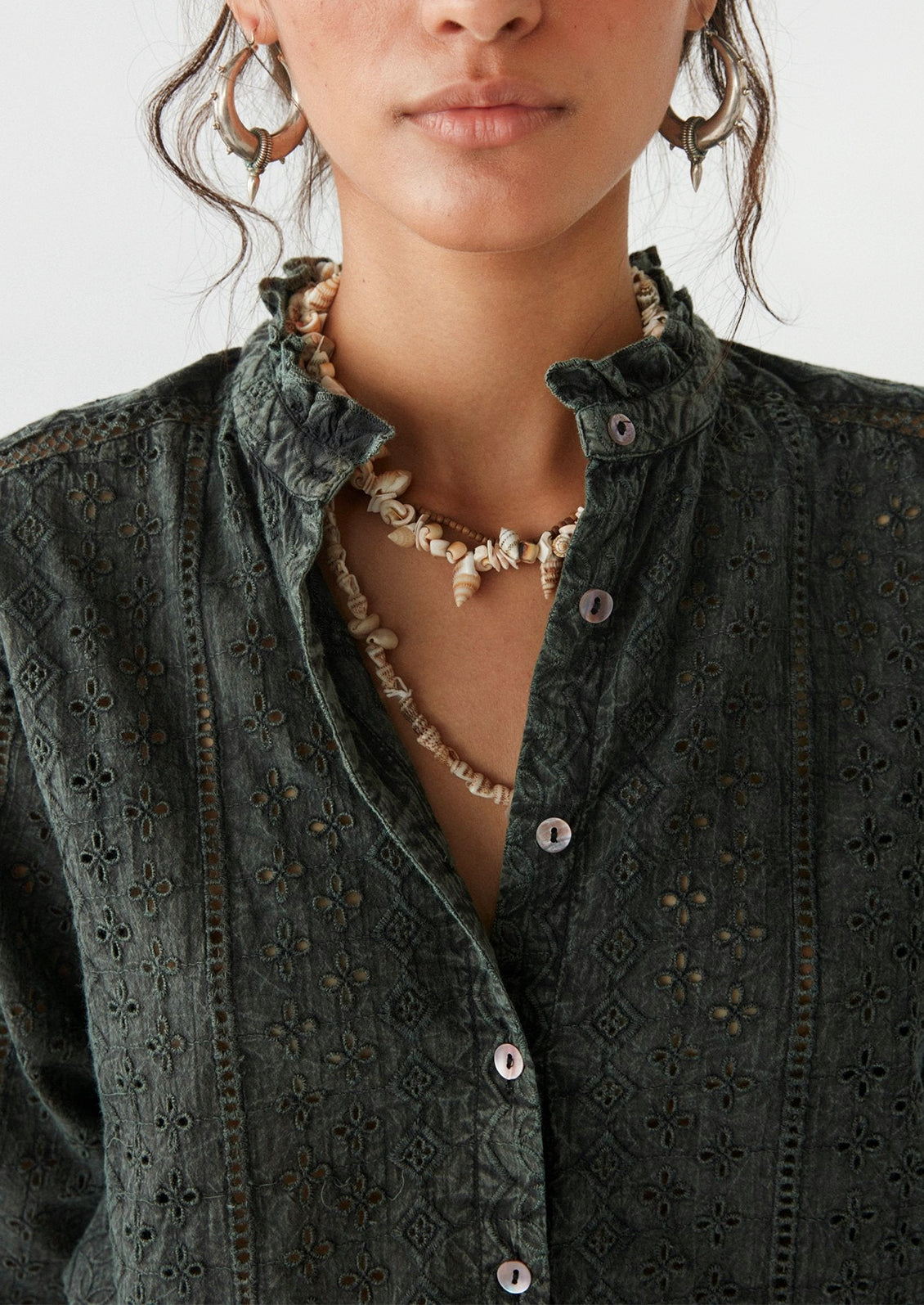 A woman wearing a dark grey cotton eyelet blouse.