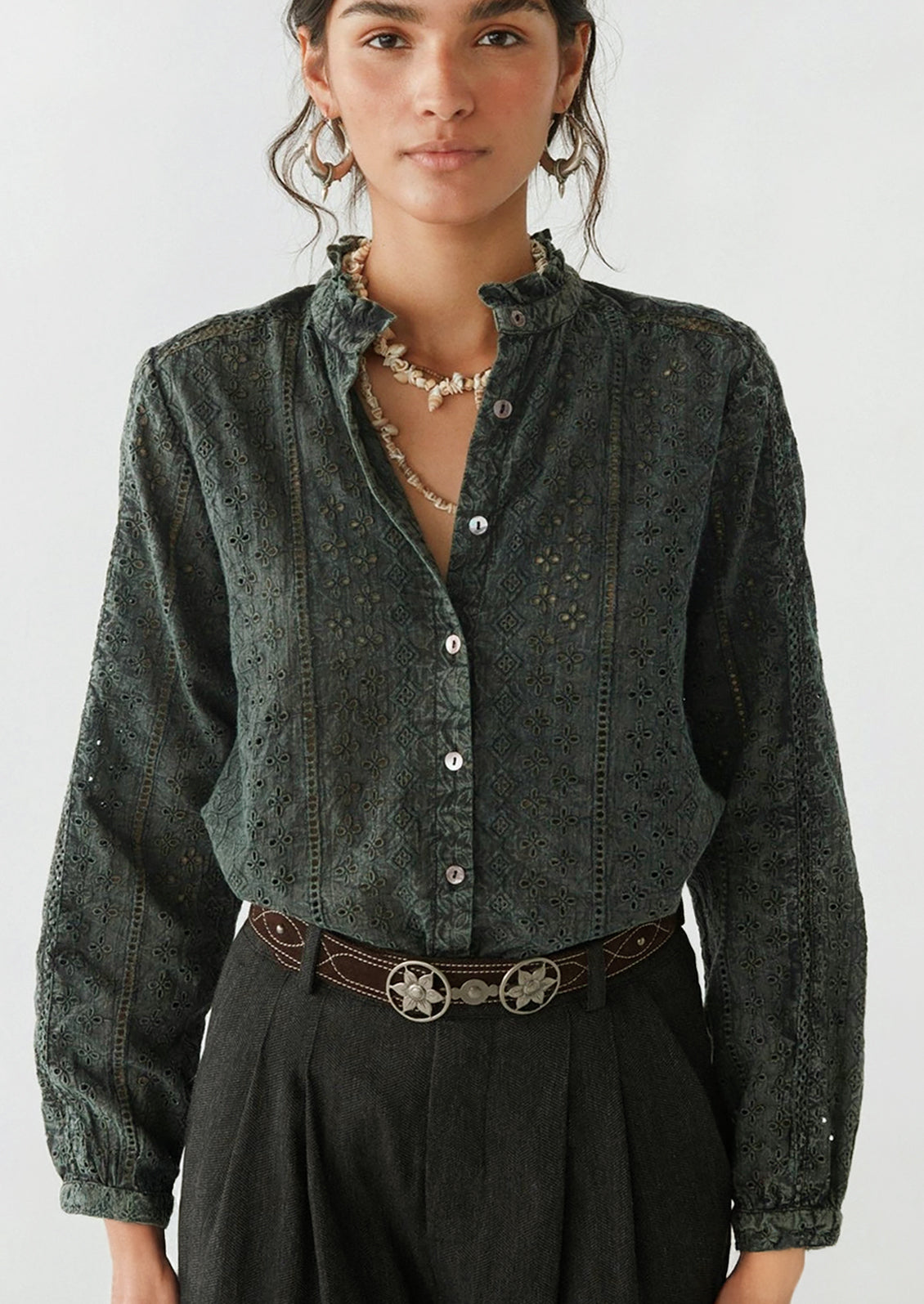 A woman wearing a dark grey cotton eyelet blouse.