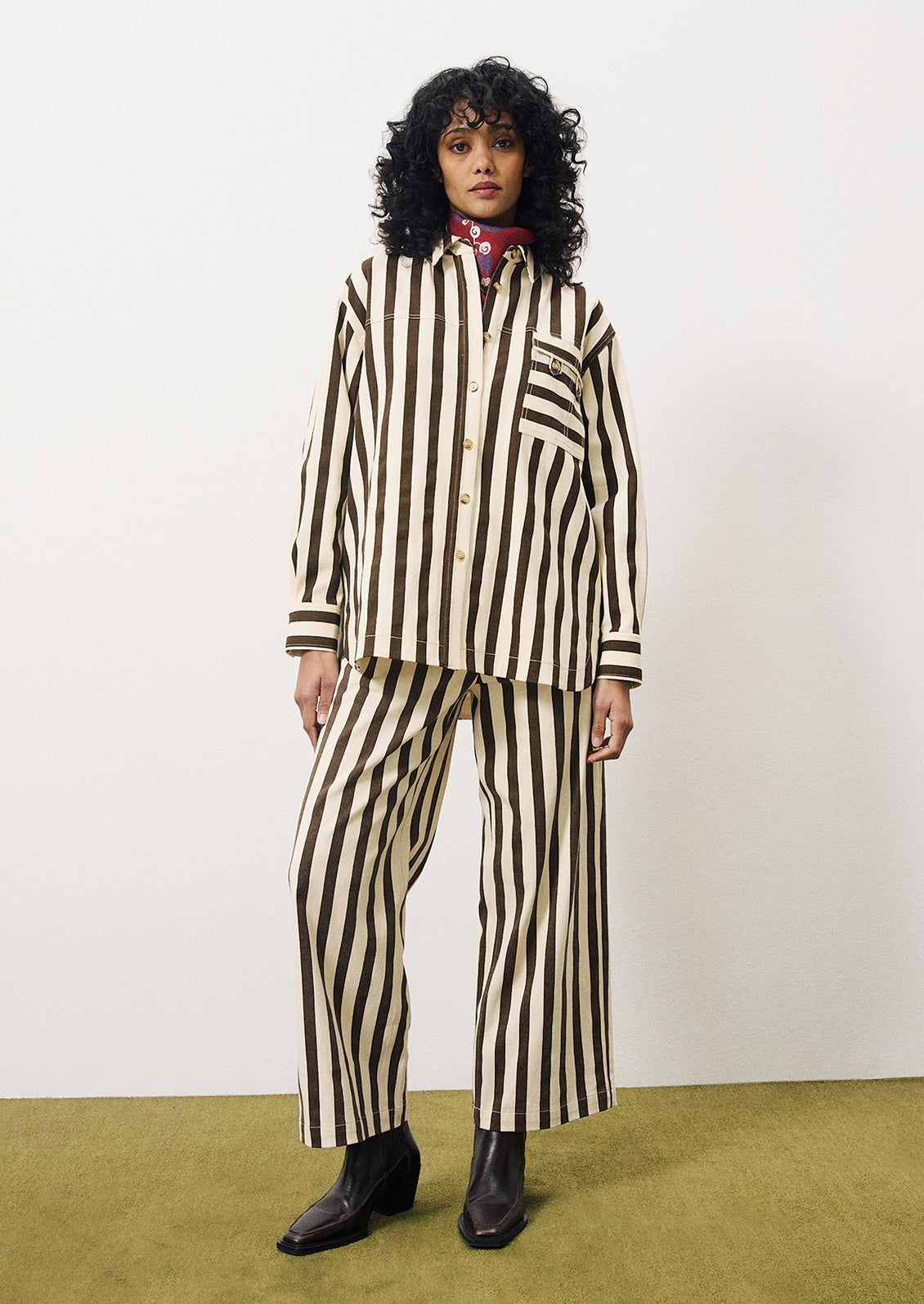 A woman wearing a cargo style button up shirt with vertical thick dark brown stripes on cream.