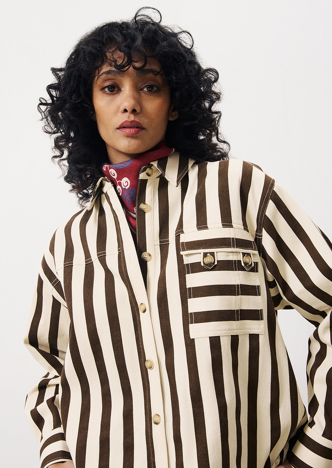 A woman wearing a cargo style button up shirt with vertical thick dark brown stripes on cream.