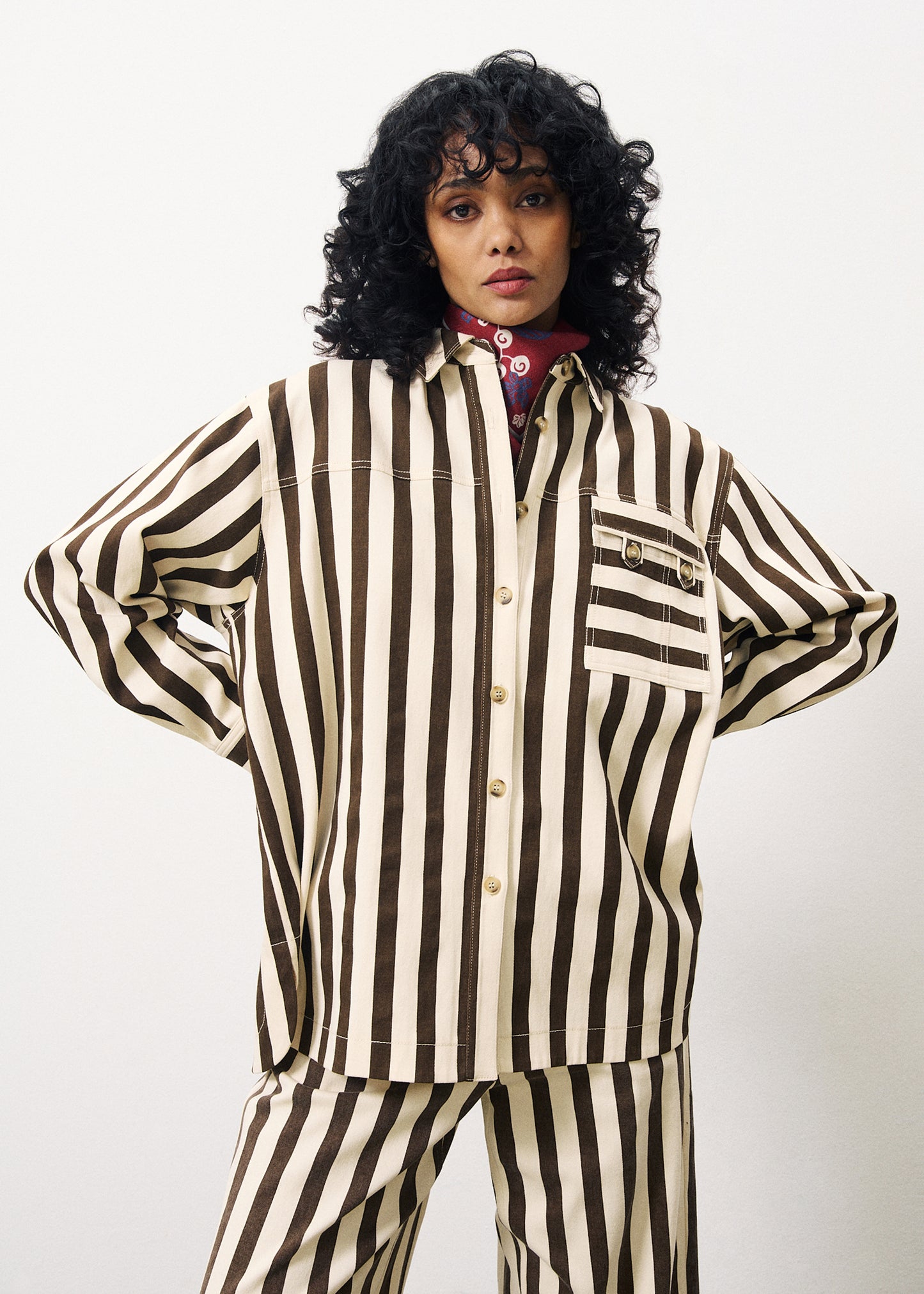 A woman wearing a cargo style button up shirt with vertical thick dark brown stripes on cream.