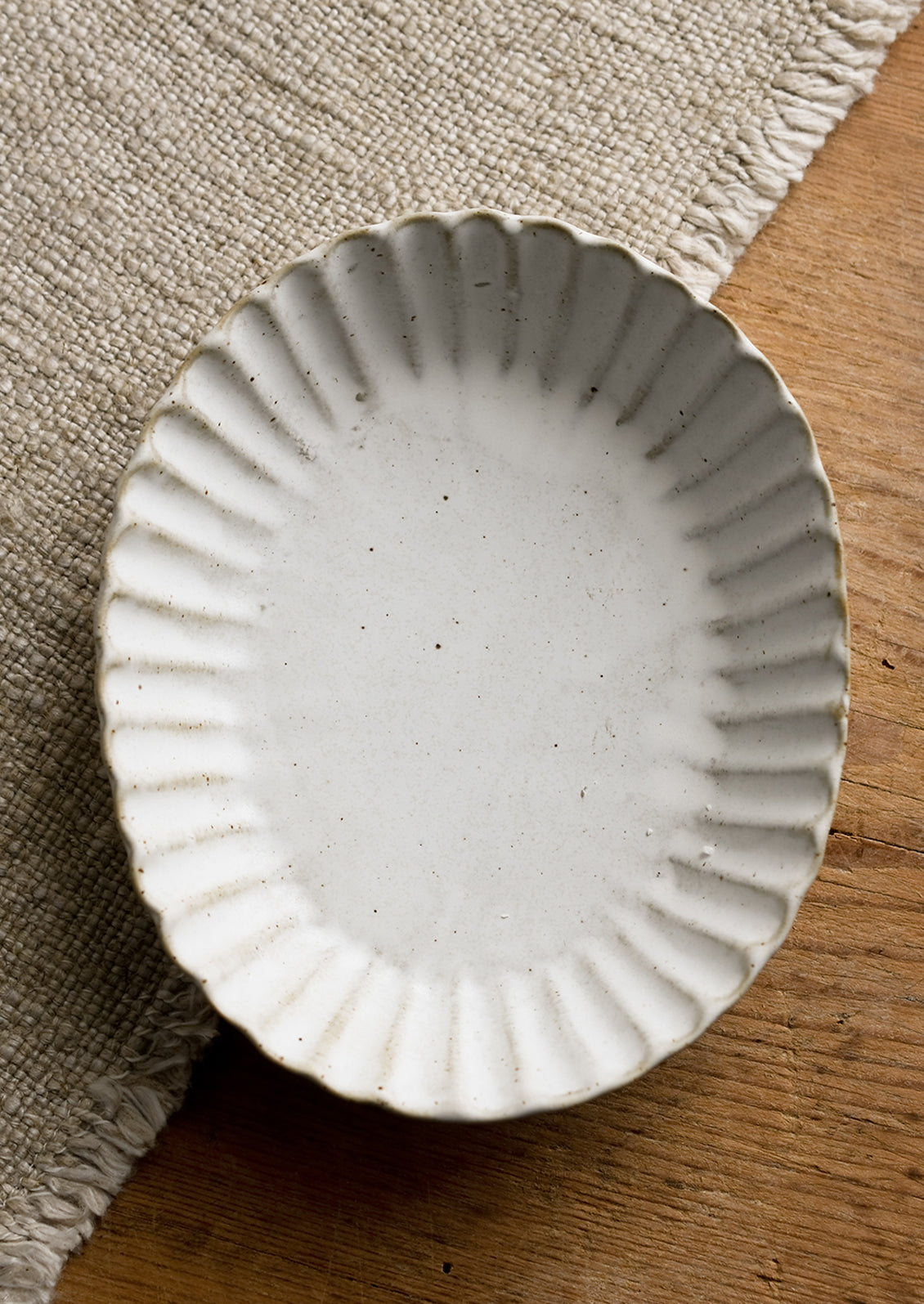 A pleated stoneware dish in oval shape.