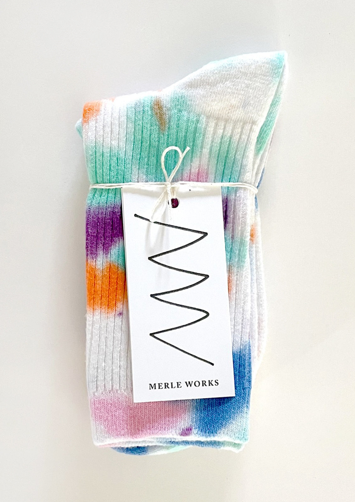 A pair of tie dye socks in white with bright aqua, blue, orange, pink and purple.