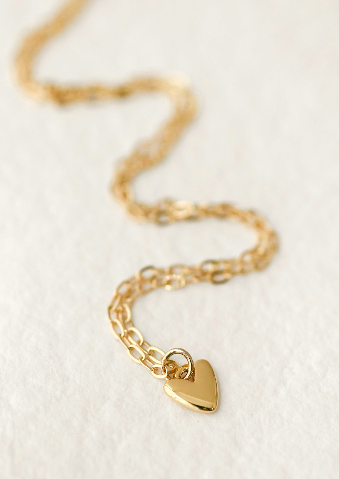 A gold chain necklace with a mini heart charm.