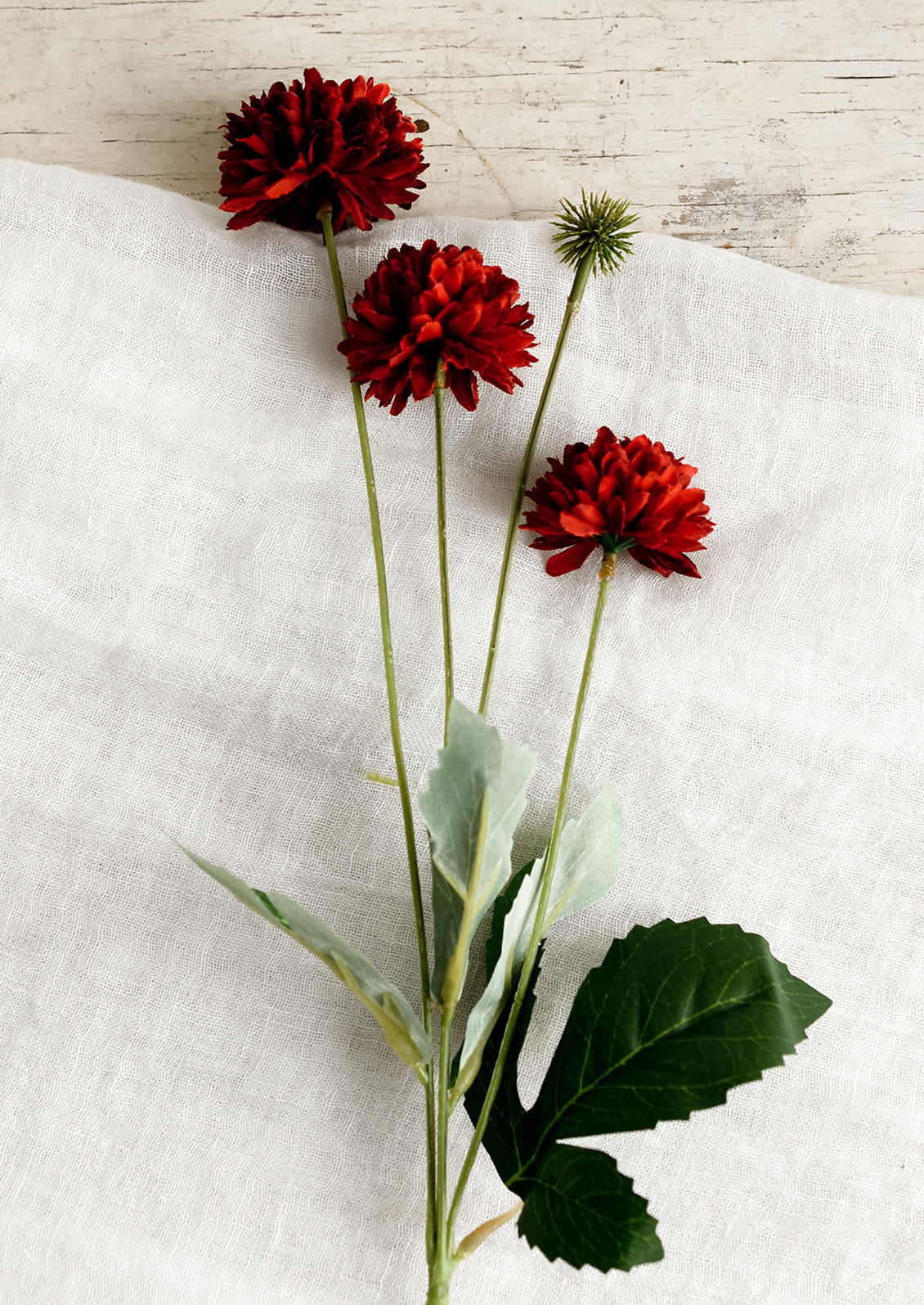 An artificial flower spray in the style of a red mum.