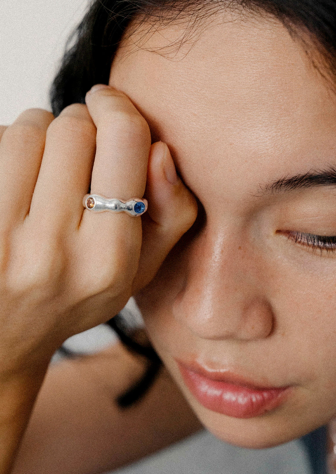 A woman wearing a unique sterling silver ring with various colored gems.