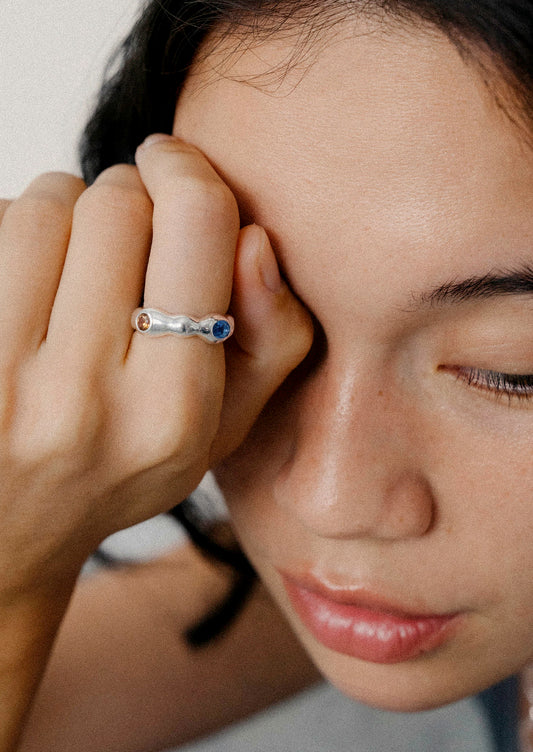 A woman wearing a unique sterling silver ring with various colored gems.
